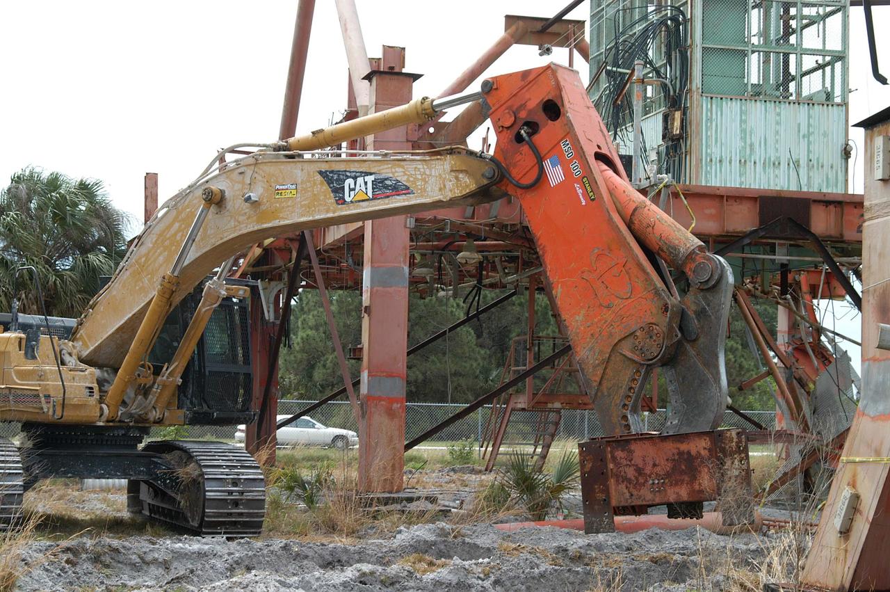 KENNEDY SPACE CENTER, FLA. -- Looking like a prehistoric monster crunching on its prey, the Caterpillar excavator and 48-inch shear attachment tear down Launch Umbilical Tower No. 1 (LUT-1) stored in the Industrial Area of KSC.  The LUT-1 was part of the launch system used for Apollo-Saturn V, launching Apollo 8, Apollo 11, Skylab manned missions and the Apollo-Soyuz Test Project.  The shear is one used in the deconstruction of the Twin Towers in New York City after 9/11.
