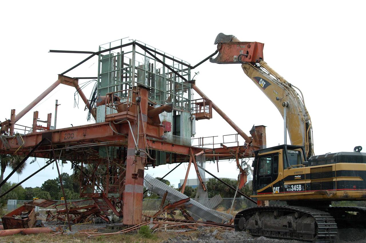 KENNEDY SPACE CENTER, FLA. -- Launch Umbilical Tower No. 1 (LUT-1) stored in the Industrial Area of KSC is being demolished with a Caterpillar excavator and 48-inch shear attachment.  Seen is the base of tower; the upright tower extended more than 398 feet above the launch pad.  The LUT-1 was part of the launch system used for Apollo-Saturn V, launching Apollo 8, Apollo 11, Skylab manned missions and the Apollo-Soyuz Test Project.  The shear is one used in the deconstruction of the Twin Towers in New York City after 9/11.