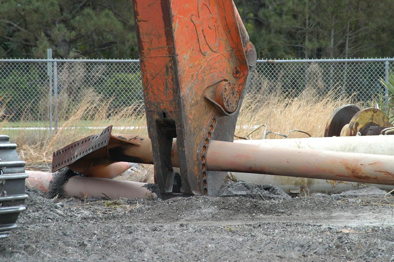KENNEDY SPACE CENTER, FLA. -- Like a dinosaur crunching on its prey, the Caterpillar excavator and 48-inch shear attachment tear down Launch Umbilical Tower No. 1 (LUT-1) stored in the Industrial Area of KSC.  The LUT-1 was part of the launch system used for Apollo-Saturn V, launching Apollo 8, Apollo 11, Skylab manned missions and the Apollo-Soyuz Test Project.  The shear is one used in the deconstruction of the Twin Towers in New York City after 9/11.