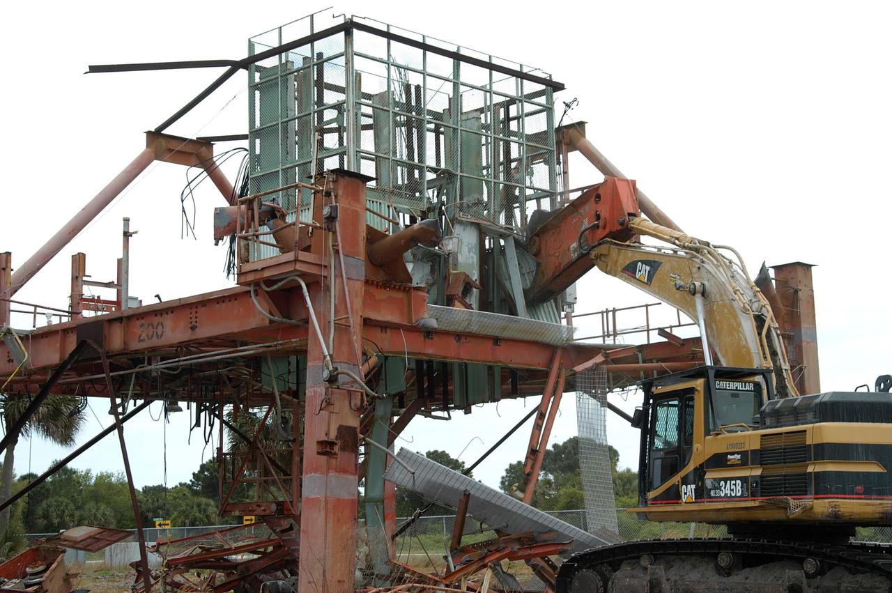 KENNEDY SPACE CENTER, FLA. -- Launch Umbilical Tower No. 1 (LUT-1) stored in the Industrial Area of KSC is being demolished with the Caterpillar excavator and 48-inch shear attachment.  Seen is the base of tower; the upright tower extended more than 398 feet above the launch pad.  The LUT-1 was part of the launch system used for Apollo-Saturn V, launching Apollo 8, Apollo 11, Skylab manned missions and the Apollo-Soyuz Test Project.  The shear is one used in the deconstruction of the Twin Towers in New York City after 9/11.