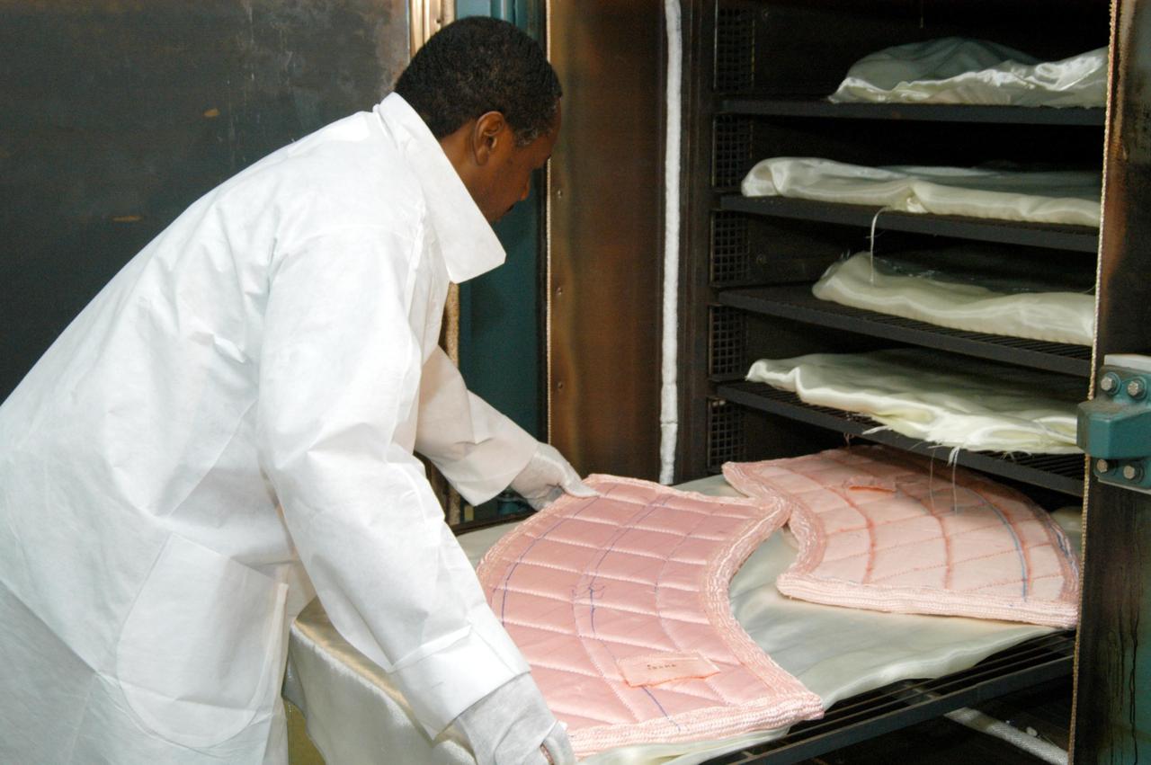 KENNEDY SPACE CENTER, FLA. -- Damon Petty, with United Space Alliance, places pieces of insulation blanket into an “oven” for heat cleaning. The blankets fit inside the nose cap of an orbiter. They consist of layered, pure silica felt sandwiched between a layer of silica fabric (the hot side) and a layer of S-Glass fabric. The blanket is through-stitched with pure silica thread in a 1-inch grid pattern. After fabrication, the blanket is bonded directly to the vehicle structure and finally coated with a high purity silica coating that improves erosion resistance. The blankets are semi-rigid and can be made as large as 30 inches by 30 inches.