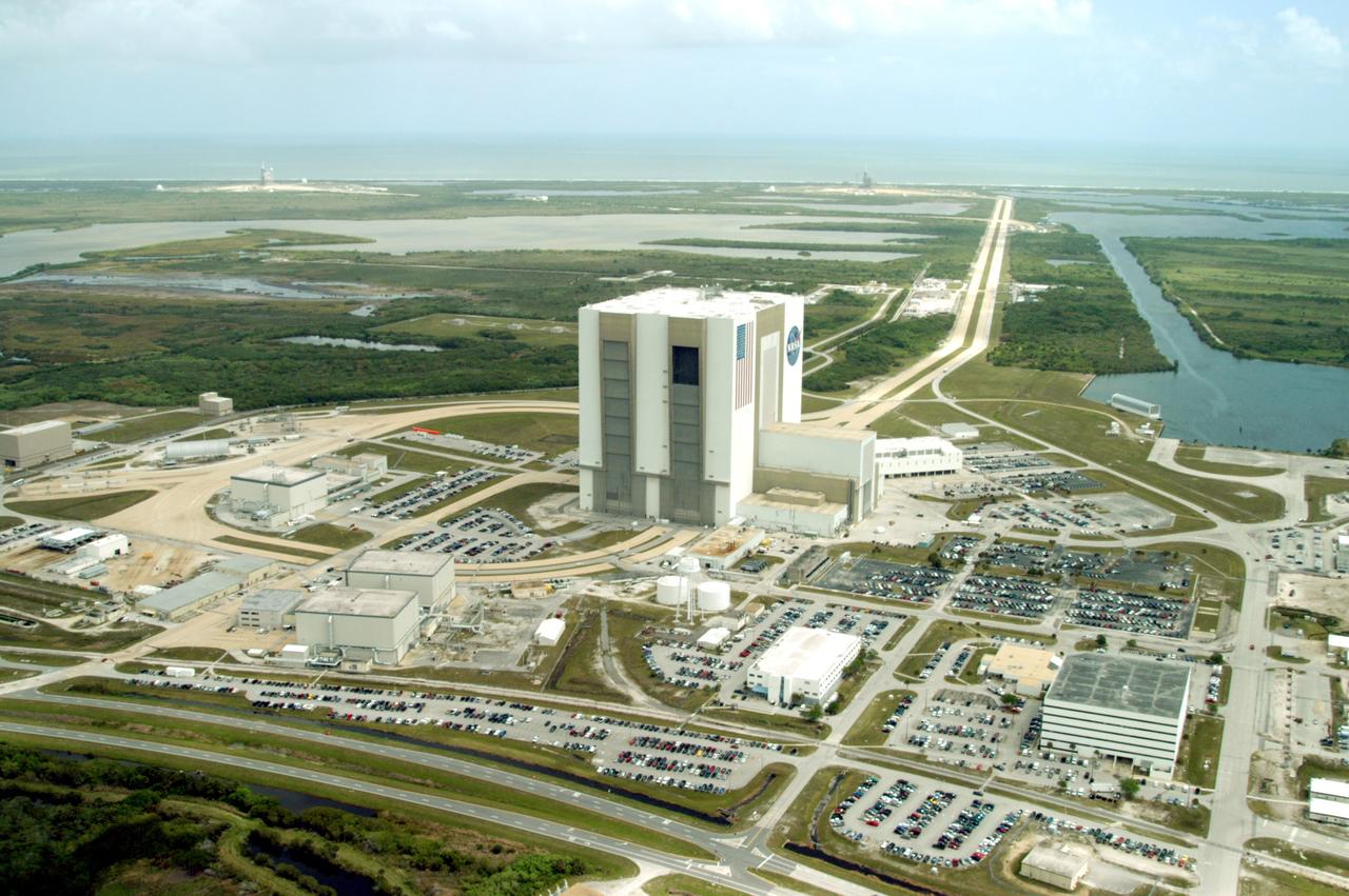 CAPE CANAVERAL, Fla. -- This aerial photo shows the expanse of the Launch Complex 39 Area, bordered on the east by the Atlantic Ocean and cloud-filled sky.  At center right, towering above the surrounding sites, is the Vehicle Assembly Building.  To the left, or north, is the Orbiter Processing Facility’s Bay 3.  On the western side are OPF Bays 1 and 2.  In the lower right corner is the Operations Support Building.  The two-lane crawlerway stretches from the VAB toward the coast, site of Launch Pad 39A, closest, and Launch Pad 39B, far left.  Between the VAB and the ocean sprawl the Banana Creek and the Banana River.  The turn basin, at right, allows delivery of external tanks that are offloaded close to and transported to the VAB.          Photo credit: NASA