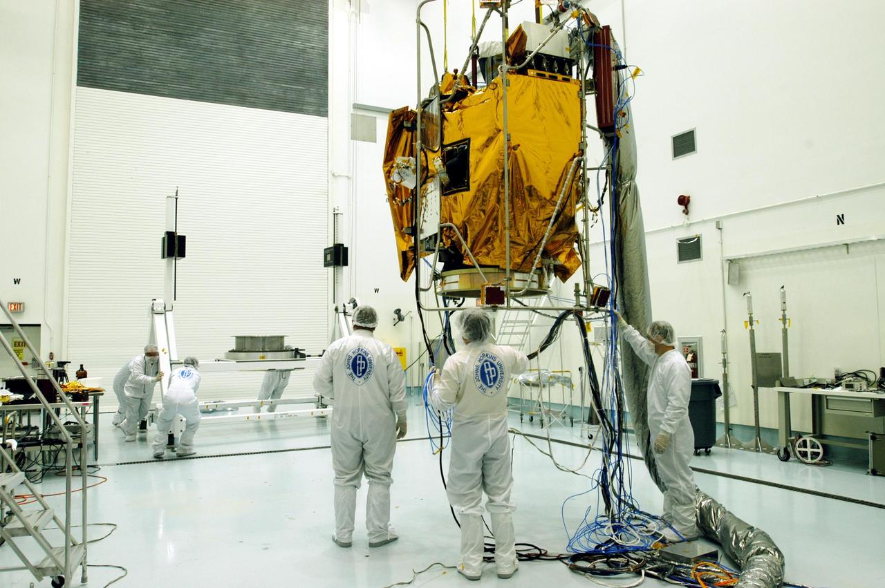 KENNEDY SPACE CENTER, FLA. -- At Astrotech Space Operations facilities near KSC, workers at left move a turnover fixture toward the Mercury Surface, Space Environment, Geochemistry and Ranging (MESSENGER) spacecraft.  The turnover fixture will rotate the spacecraft for prelaunch testing.   MESSENGER is undergoing prelaunch testing at the site.  Launch is scheduled for May 11 from Pad 17-B, Cape Canaveral Air Force Station. The spacecraft will fly past Venus three times and Mercury twice before starting a year-long orbital study of Mercury in July 2009.