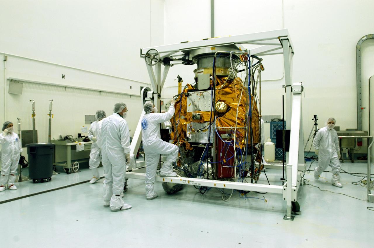 KENNEDY SPACE CENTER, FLA. -- Astrotech Space Operations facilities near KSC, workers check the Mercury Surface, Space Environment, Geochemistry and Ranging (MESSENGER) spacecraft after completing rotation on the turnover fixture. Workers will perform the propulsion system phasing test - firing gas through the thrusters in order to verify that the right thrusters fire when expected - as part of prelaunch testing at the site. Launch is scheduled for May 11 from Pad 17-B, Cape Canaveral Air Force Station. The spacecraft will fly past Venus three times and Mercury twice before starting a year-long orbital study of Mercury in July 2009.
