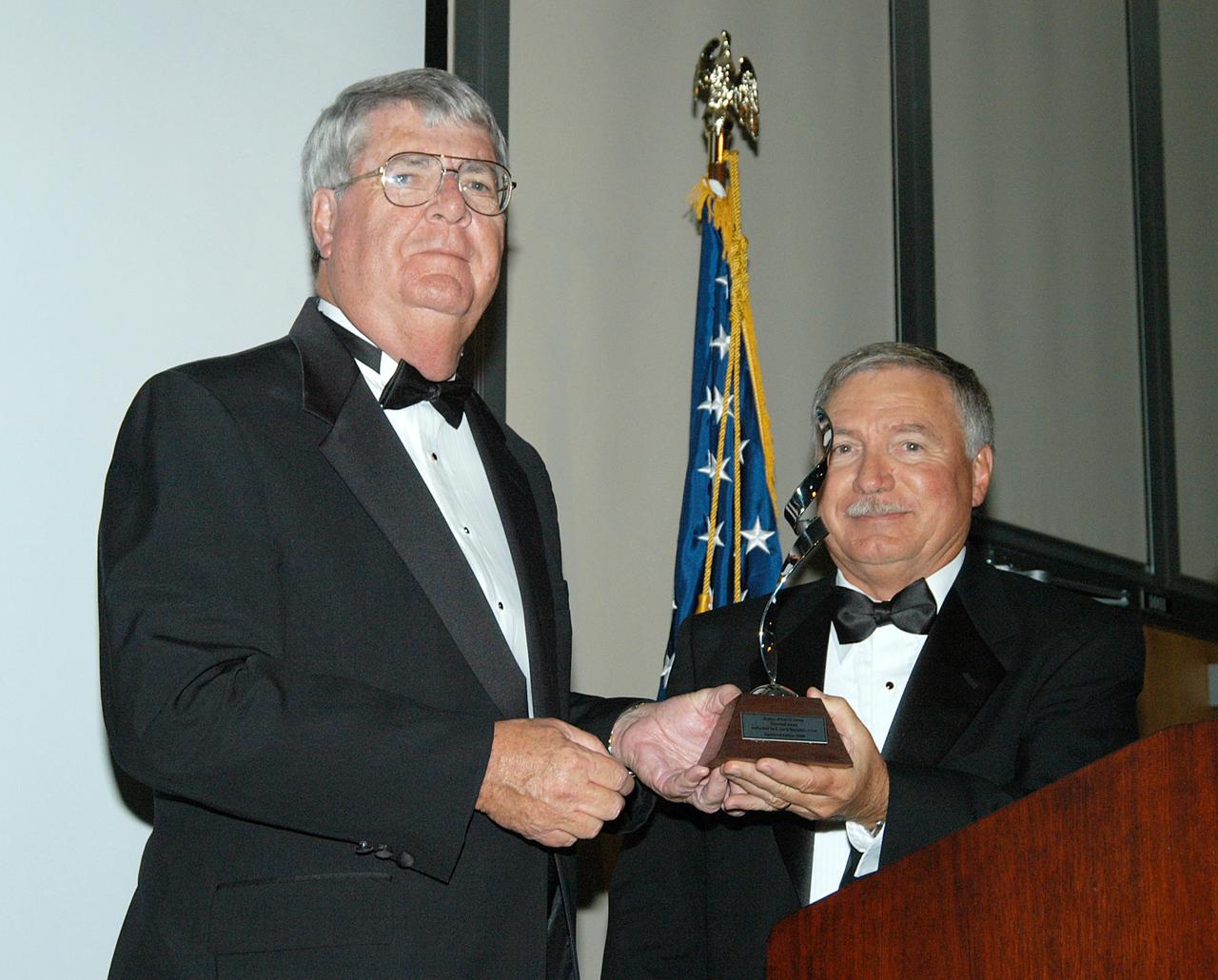 KENNEDY SPACE CENTER, FLA. -- At the annual National Space Club Debus Award Banquet, Master of Ceremonies Dick Beagley (left) presents the Debus Award to John J. “Tip” Talone, director of the International Space Station/Payloads Processing directorate. He was honored for his outstanding personal and professional efforts in supporting the U.S. space program, especially in his current role. The event was held at the Dr. Kurt H. Debus Conference Facility in the Visitor Complex. The award was created by the National Space Club to recognize significant achievements and contributions made in Florida to American aerospace efforts. It is named for Dr. Kurt H. Debus, first director of KSC, from 1962 to 1974.