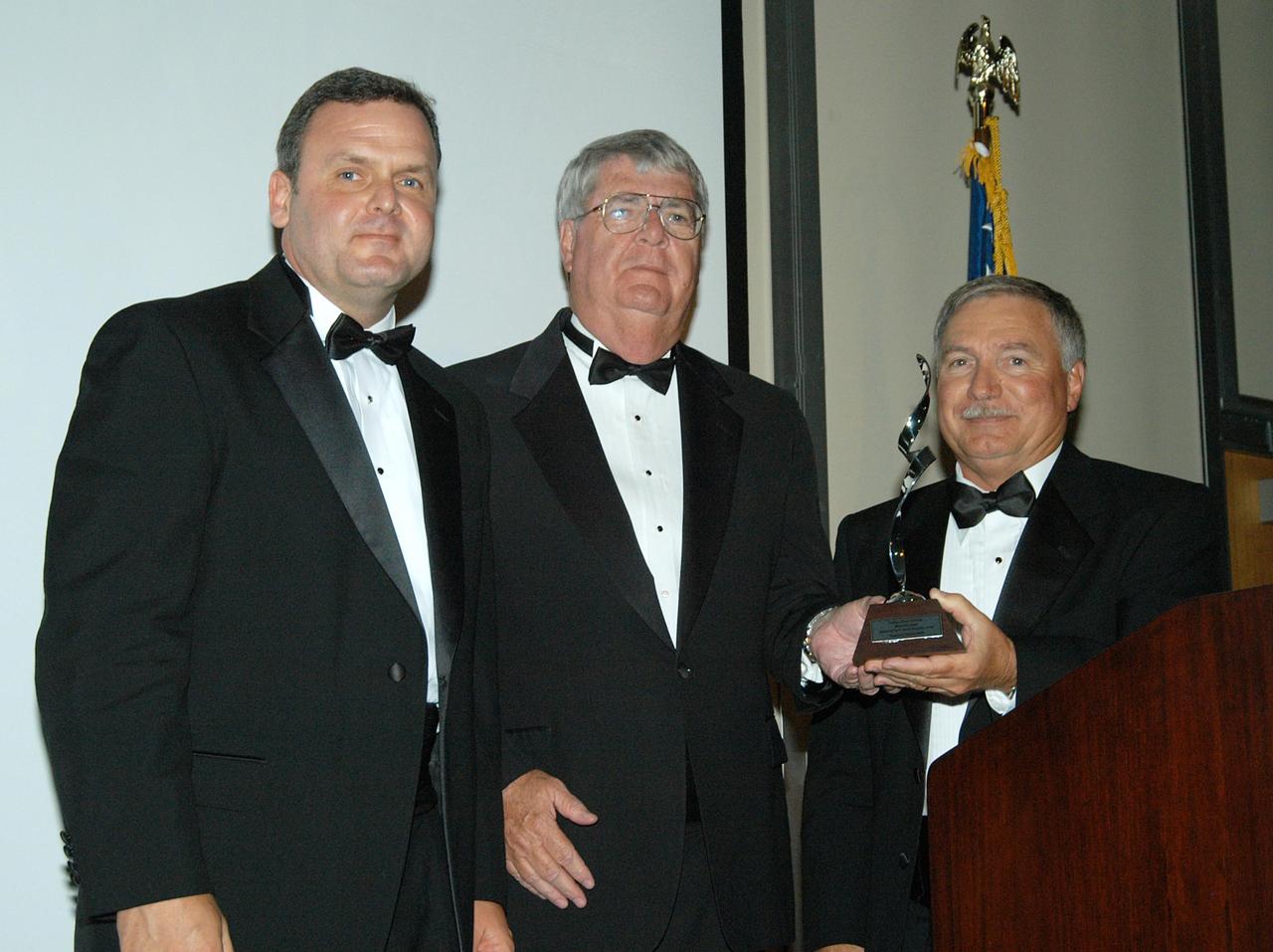 KENNEDY SPACE CENTER, FLA. -- Jim Chilton (left), CAPPS program manager, and Dick Beagley, chairman of the National Space Club Debus Award Banquet committee, present the 2004 Debus Award to John J. “Tip” Talone (right). The event was held at the Dr. Kurt H. Debus Conference Facility in the Visitor Complex. Talone is director of the International Space Station/Payloads Processing directorate at KSC that is responsible for prelaunch and launch preparations for all Shuttle payloads. He was honored for his outstanding personal and professional efforts in supporting the U.S. space program, especially in his current role. The award was created by the National Space Club Florida Committee to recognize significant achievements and contributions made in Florida to American aerospace efforts. It is named for Dr. Kurt H. Debus, first director of KSC, from 1962 to 1974.