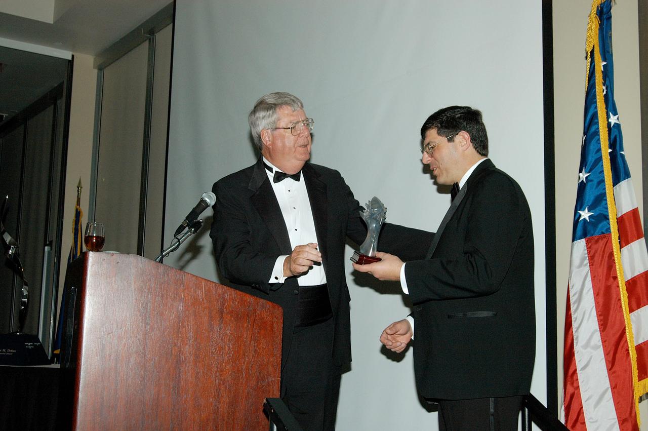 KENNEDY SPACE CENTER, FLA. -- At the annual National Space Club Debus Award Banquet, held at the Dr. Kurt H. Debus Conference Facility in the KSC Visitor Complex, Master of Ceremonies Dick Beagley (left) presents a memento to guest speaker Christopher Scolese, who is the deputy associate administrator in the Office of Space Science at NASA Headquarters. KSC’s Director of the International Space Station/Payloads Processing directorate John J. “Tip” Talone received the Debus award. He was honored for his outstanding personal and professional efforts in supporting the U.S. space program, especially in his current role. Beagley is chairman of the National Space Club Florida Committee, which created the award to recognize significant achievements and contributions made in Florida to American aerospace efforts. It is named for Dr. Kurt H. Debus, first director of KSC, from 1962 to 1974.