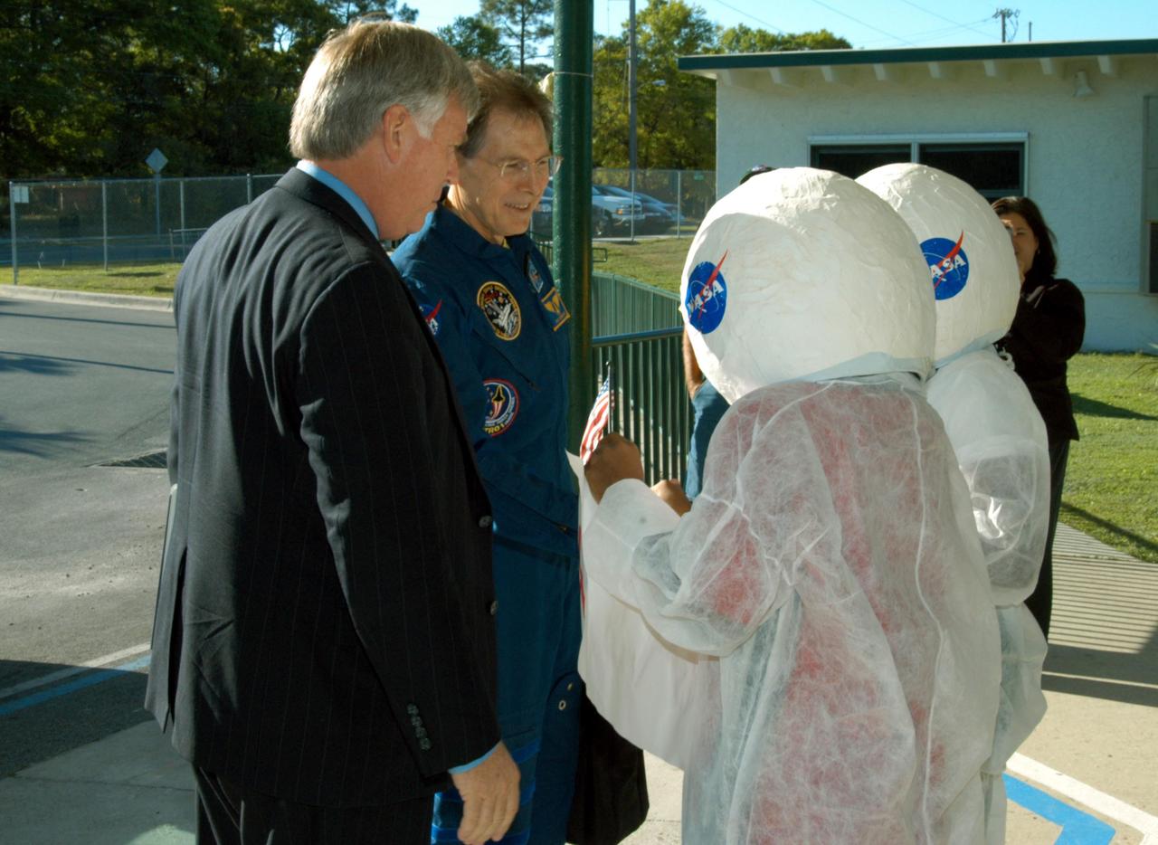 KENNEDY SPACE CENTER, FLA. -- Two student “astronauts” welcome Center Director Jim Kennedy (left) and NASA astronaut Sam Durrance to Oscar Patterson Elementary Magnet School in Panama City, Fla. Kennedy and other NASA-KSC representatives are visiting NASA Explorer Schools in Florida and Georgia to share America’s new vision  for space exploration with the next generation of explorers. Kennedy is talking with students about our destiny as explorers, NASA’s stepping stone approach to exploring Earth, the Moon, Mars and beyond, how space impacts our lives, and how people and machines rely on each other in space.