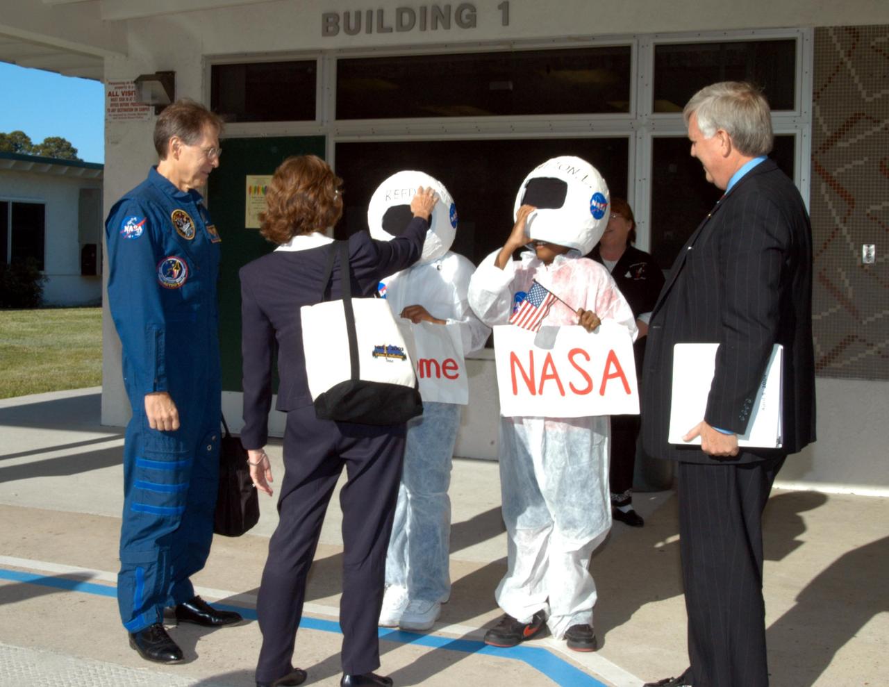 KENNEDY SPACE CENTER, FLA. -- Pam Biegert (back to camera), chief of KSC’s Education Programs and University Research Office, praises the costumes of two students who welcomed NASA representatives to Oscar Patterson Elementary Magnet School in Panama City, Fla. At left is astronaut Sam Durrance, and at right is Center Director Jim Kennedy.  NASA-KSC officials are visiting NASA Explorer Schools in Florida and Georgia to share America’s new vision  for space exploration with the next generation of explorers. Kennedy is talking with students about our destiny as explorers, NASA’s stepping stone approach to exploring Earth, the Moon, Mars and beyond, how space impacts our lives, and how people and machines rely on each other in space.