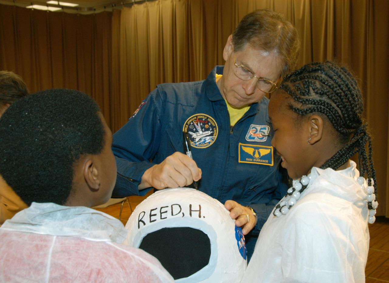 KENNEDY SPACE CENTER, FLA. -- Astronaut Sam Durrance signs the costume helmet of one of the students who welcomed NASA representatives to Oscar Patterson Elementary Magnet School in Panama City, Fla.  He and Center Director Jim Kennedy, along with others, visited the school to share America’s new vision for space exploration with the next generation of explorers. Kennedy is talking with students about our destiny as explorers, NASA’s stepping stone approach to exploring Earth, the Moon, Mars and beyond, how space impacts our lives, and how people and machines rely on each other in space.