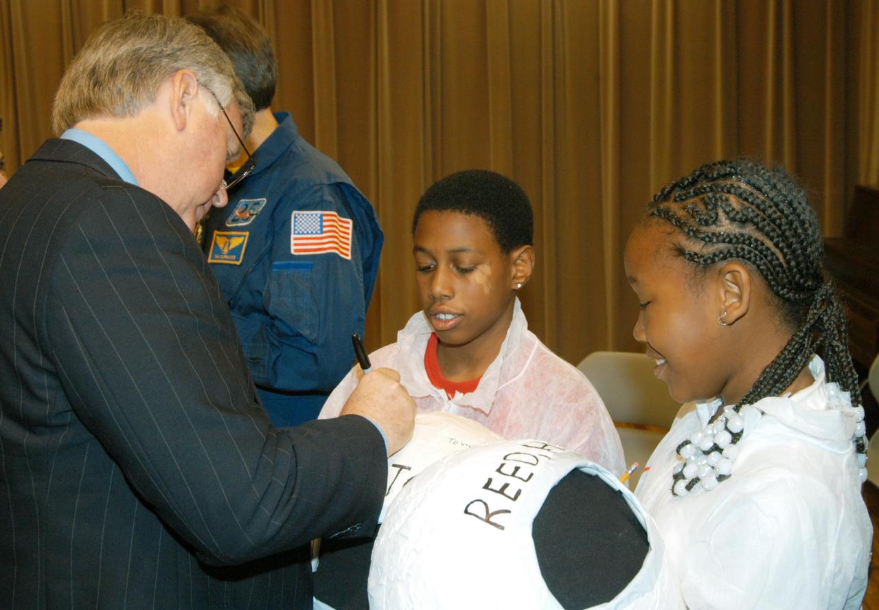 KENNEDY SPACE CENTER, FLA. -- Center Director Jim Kennedy signs the costume helmet of one of the students who welcomed NASA representatives to Oscar Patterson Elementary Magnet School in Panama City, Fla.  He other NASA officials visited the school to share America’s new vision for space exploration with the next generation of explorers. Kennedy is talking with students at NASA Explorer Schools in Florida and Georgia about our destiny as explorers, NASA’s stepping stone approach to exploring Earth, the Moon, Mars and beyond, how space impacts our lives, and how people and machines rely on each other in space.