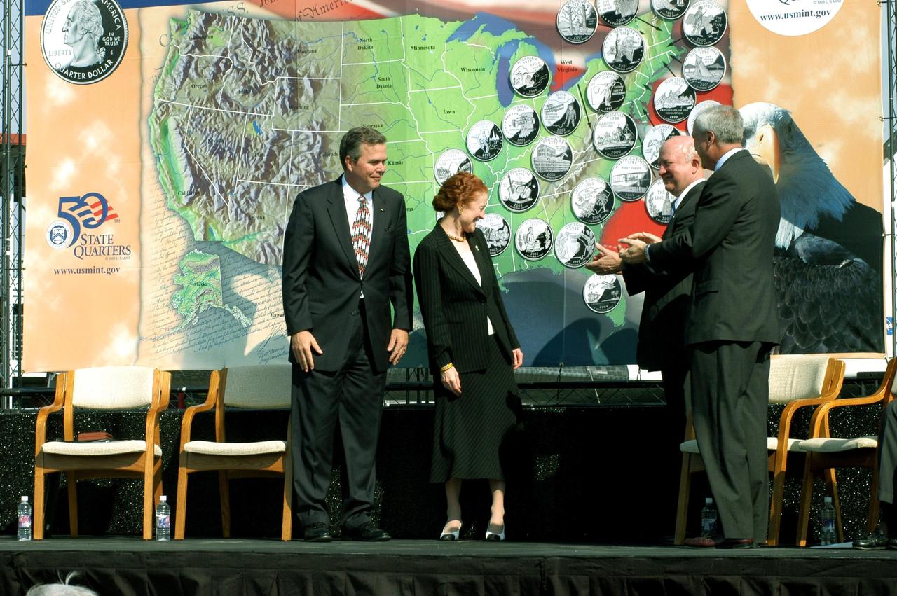 KENNEDY SPACE CENTER, FLA. -- From left, Florida Gov. Jeb Bush, U.S. Mint Director Henrietta Holsman Fore, Deputy Secretary of the Treasury Samuel W. Bodman, and NASA Administrator Sean O’Keefe participate in the launching ceremony for the new Florida quarter, held at the KSC Visitor Complex. In the background is a map of the United States illustrating the state quarters issued to date. The newly unveiled quarter celebrates Florida as the gateway to discovery -- a destination for explorers in the past, a launch site for space explorers of the future, and an inviting place for visitors today.