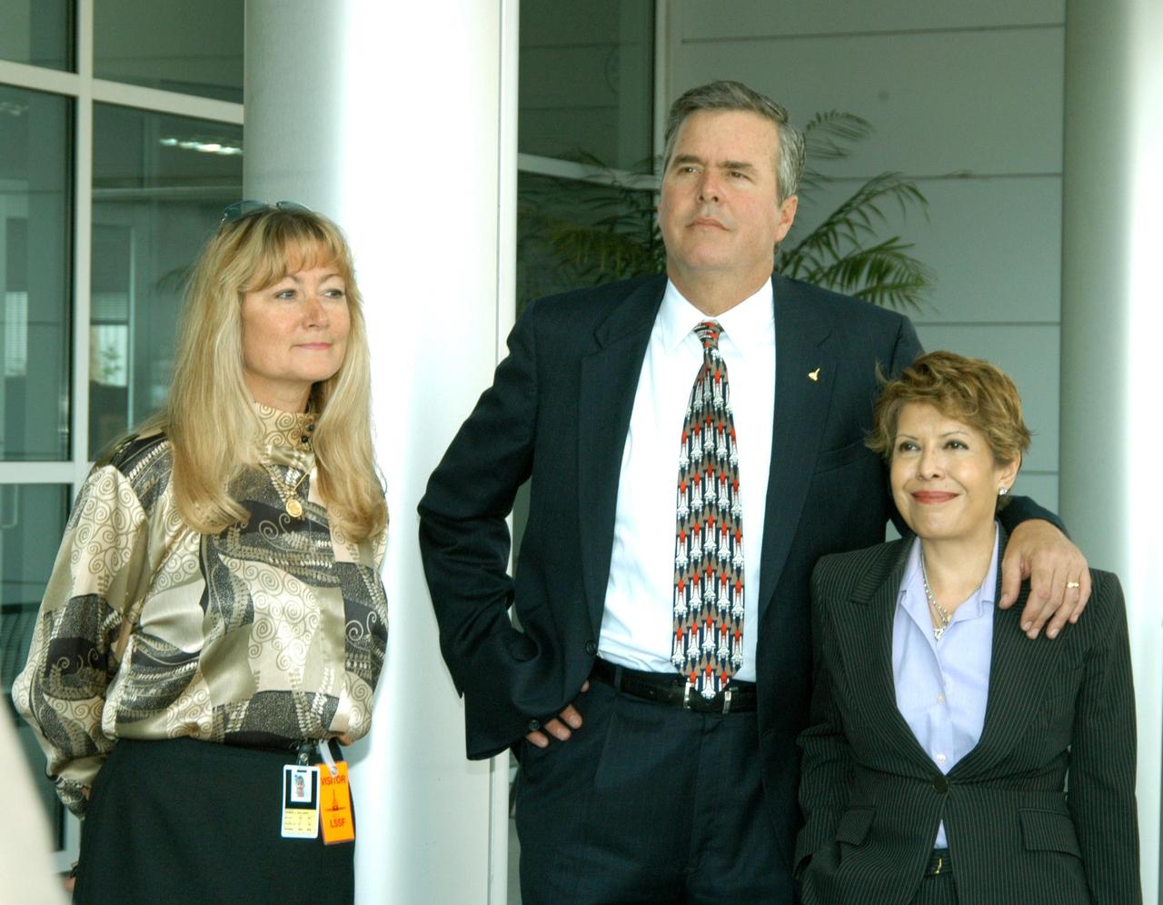 KENNEDY SPACE CENTER, FLA. --  Florida Gov. Jeb Bush and his wife, Columba (right), wait outside the KSC Space Life Sciences (SLS) Lab for a tour.  At left is Debra Holliday, director of Business Development and International Affairs, Florida Spaceport Authority.  The new lab is a state-of-the-art facility built for ISS biotechnology research. It was developed as a partnership between NASA-KSC and the State of Florida.  The tour followed the launching ceremony at the KSC Visitor Complex for the new Florida quarter issued by the U.S. Mint. The ceremony was emceed by Kennedy and included remarks by NASA Administrator Sean O’Keefe, Gov. Jeb Bush, U.S. Mint Director Henrietta Holsman Fore and Deputy Secretary of the Treasury Samuel W. Bodman. On the tour, Gov. Bush was accompanied by NASA Administrator Sean O’Keefe and Center Director Jim Kennedy and their wives.