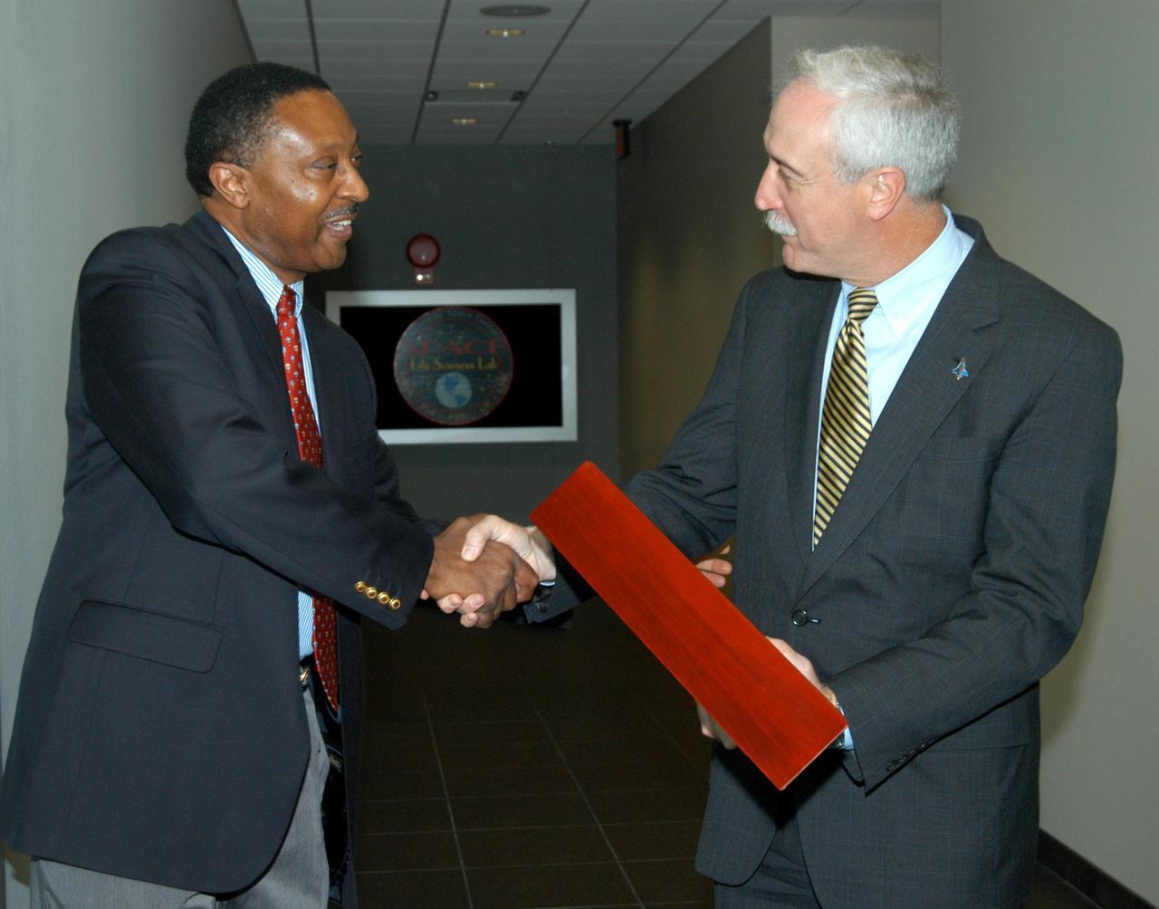 KENNEDY SPACE CENTER, FLA. -- Former astronaut Winston Scott (left) presents a NASA flag flown at the KSC Space Life Sciences Lab to NASA Administrator Sean O’Keefe.  The flag was flown during construction through the dedication of the Lab. The presentation was during a tour of the Lab following the launching ceremony at the KSC Visitor Complex for the new Florida quarter issued by the U.S. Mint.  The ceremony was emceed by Center Director Jim Kennedy and included remarks by O’Keefe, Florida Gov. Jeb Bush, U.S. Mint Director Henrietta Holsman Fore and Deputy Secretary of the Treasury Samuel W. Bodman. The new lab is a state-of-the-art facility built for ISS biotechnology research. It was developed as a partnership between NASA-KSC and the State of Florida.