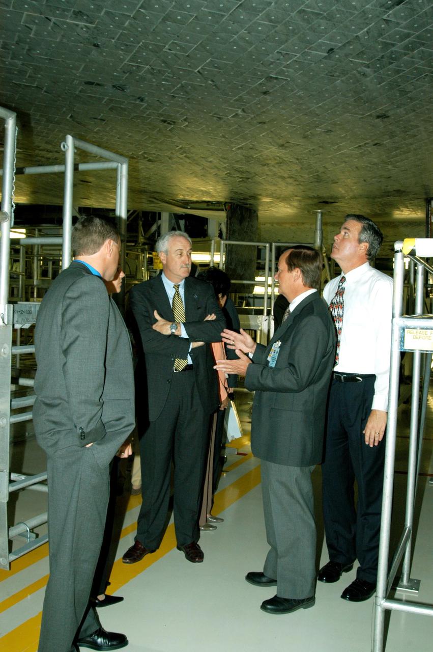 KENNEDY SPACE CENTER, FLA. -- Standing under the orbiter Atlantis, Shuttle Launch Director Mike Leinbach (second from right) provides information about the tiles and Thermal Protection System for NASA Administrator Sean O’Keefe (second from left) and Florida Gov. Jeb Bush (far right). O’Keefe and Bush toured the Orbiter Processing Facility following the launching ceremony at the KSC Visitor Complex for the new Florida quarter issued by the U.S. Mint. The ceremony was emceed by Center Director Jim Kennedy and included remarks by O’Keefe, Bush, U.S. Mint Director Henrietta Holsman Fore and Deputy Secretary of the Treasury Samuel W. Bodman.