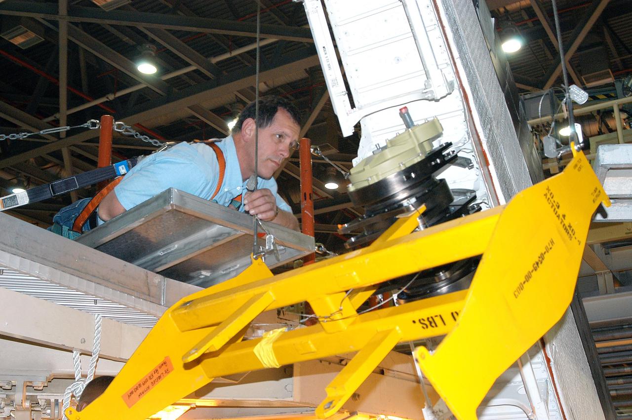 KENNEDY SPACE CENTER, FLA. - A United Space Alliance technician monitors the placement of Rudder Speed Brake actuator No.4 as work proceeds to install it on Space Shuttle orbiter Discovery in the Orbiter Processing Facility. Discovery has been assigned to the first Return to Flight mission, STS-114, a logistics flight to the International Space Station.