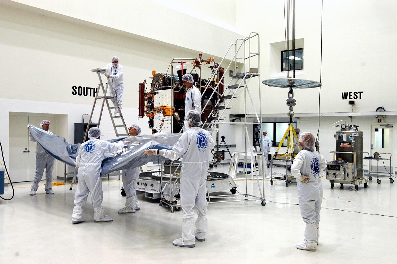 KENNEDY SPACE CENTER, FLA. - - Workers at Astrotech Space Operations in Titusville, Fla., remove the cover from the MESSENGER (Mercury Surface, Space Environment, Geochemistry and Ranging) spacecraft inside the nonhazardous payload processing facility. Final assembly and testing will be completed at this site. The spacecraft will return to the hazardous processing facility when ready for fueling, spin balance testing and mating to the upper stage. MESSENGER is scheduled to launch no earlier than July 30 from Cape Canaveral Air Force Station. MESSENGER is a scientific investigation of the planet Mercury, the least explored terrestrial planet. Understanding Mercury and how it was formed is essential to understanding the other terrestrial planets and their evolution. The MESSENGER mission will orbit Mercury after making two flybys of the planet, using data collected during the flybys as an initial guide to perform a more focused scientific investigation of this mysterious world. The spacecraft will enter Mercury orbit in March 2011 and carry out comprehensive measurements for one full Earth year.