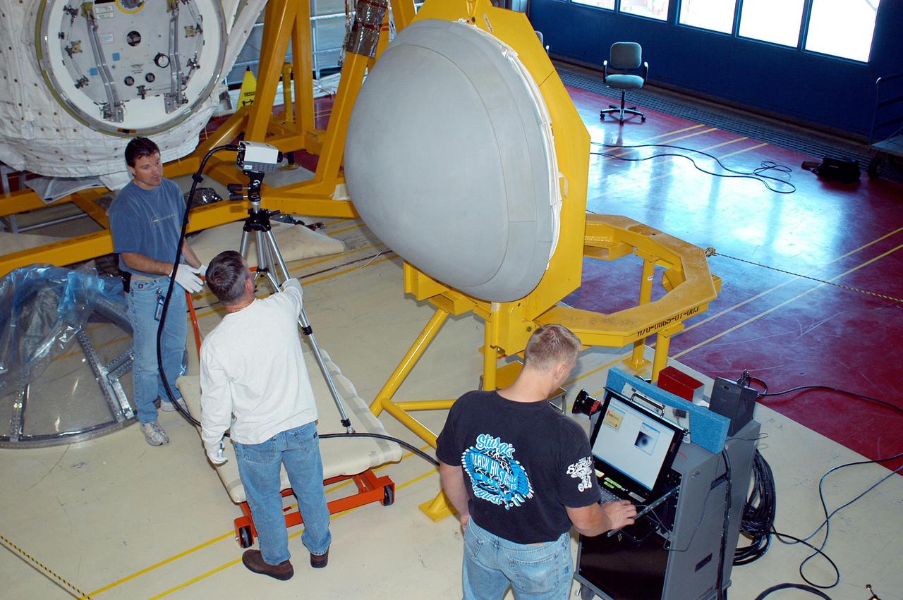 KENNEDY SPACE CENTER, FLA. - In the Orbiter Processing Facility, from left, United Space Alliance workers Ken Tauer and Paul Ogletree set up an infrared camera in front of Discovery’s nose cap while Ross Neubarth checks the monitor. The nose cap will undergo thermography to verify integrity of hardware before flight. This procedure uses high intensity light to heat areas that are immediately scanned with an infrared camera to check for internal flaws. Discovery is the vehicle assigned to the Return to Flight mission, STS-114.