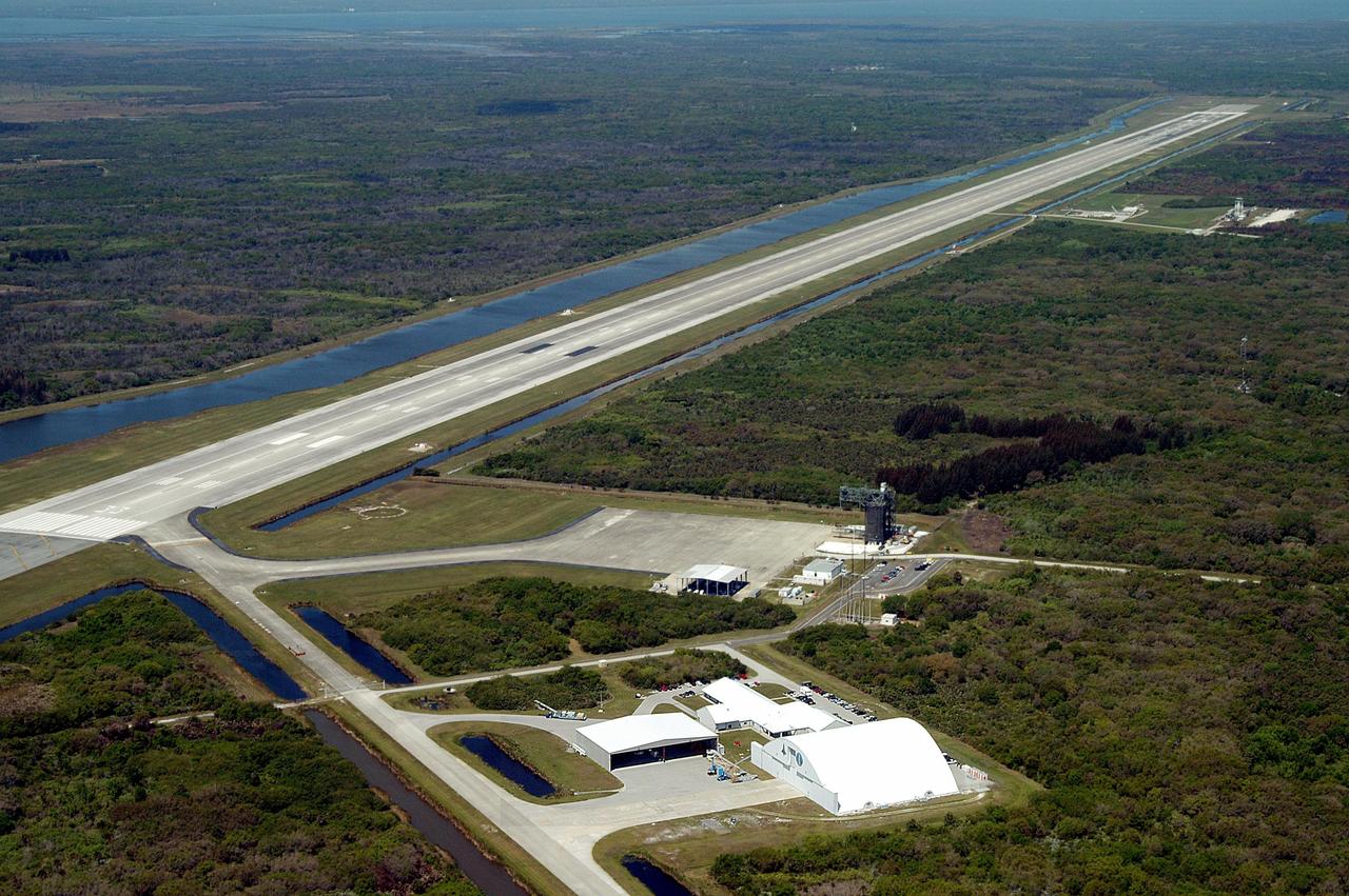KENNEDY SPACE CENTER, FLA. - This aerial photo shows the runway at the KSC Shuttle Landing Facility extending left to upper right.  Longer and wider than most commercial runways, it is 15,000 feet long, with 1,000-foot paved overruns on each end, and 300 feet wide, with 50-foot asphalt shoulders.  The runway is used by military and civilian cargo carriers, astronauts’ T-38 trainers, Shuttle Training Aircraft and helicopters, as well as the Space Shuttle.  In the foreground is the parking apron with the orbiter mate/demate tower, the hangar and other storage facilities, and the tow-way stretching from the runway to the lower center.  In the upper right is a grassy area where the new control tower is located.