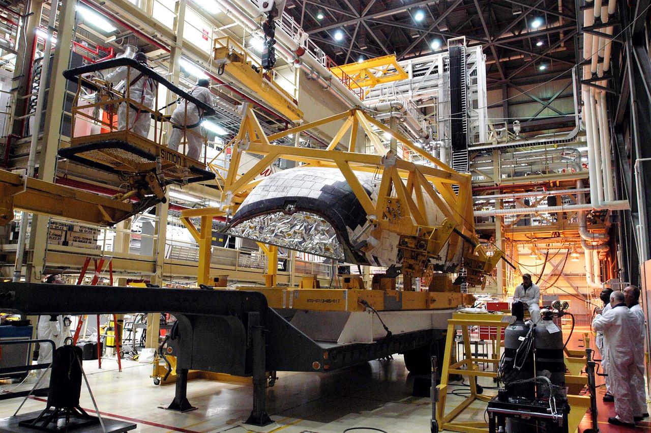KENNEDY SPACE CENTER, FLA. - In the Orbiter Processing Facility, the left-hand Orbital Maneuvering System (OMS) pod (seen from the front) is lifted off its transporter. The OMS pod will be installed on the orbiter Discovery. The Orbital Maneuvering System provides the thrust for orbit insertion, orbit circularization, orbit transfer, rendezvous, deorbit, abort to orbit and abort once around. It can provide up to 1,000 pounds of propellant to the aft reaction control system. Each pod contains one OMS engine and the hardware needed to pressurize, store and distribute the propellants to perform the velocity maneuvers.