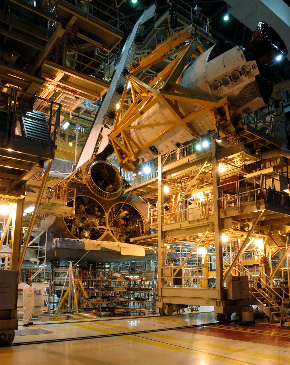 KENNEDY SPACE CENTER, FLA. - In the Orbiter Processing Facility, the left-hand Orbital Maneuvering System (OMS) pod (top of photo) is poised behind the engine interfaces on the orbiter Discovery for installation. The Orbital Maneuvering System provides the thrust for orbit insertion, orbit circularization, orbit transfer, rendezvous, deorbit, abort to orbit and abort once around. It can provide up to 1,000 pounds of propellant to the aft reaction control system. Each pod contains one OMS engine and the hardware needed to pressurize, store and distribute the propellants to perform the velocity maneuvers.