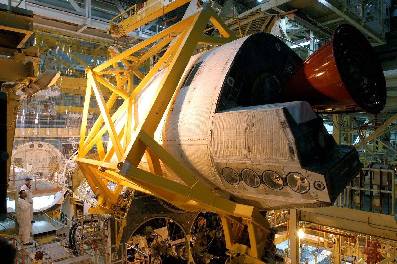 KENNEDY SPACE CENTER, FLA. - In the Orbiter Processing Facility, the left-hand Orbital Maneuvering System (OMS) pod is maneuvered toward the engine interfaces on the orbiter Discovery for installation. The Orbital Maneuvering System provides the thrust for orbit insertion, orbit circularization, orbit transfer, rendezvous, deorbit, abort to orbit and abort once around. It can provide up to 1,000 pounds of propellant to the aft reaction control system. Each pod contains one OMS engine and the hardware needed to pressurize, store and distribute the propellants to perform the velocity maneuvers.