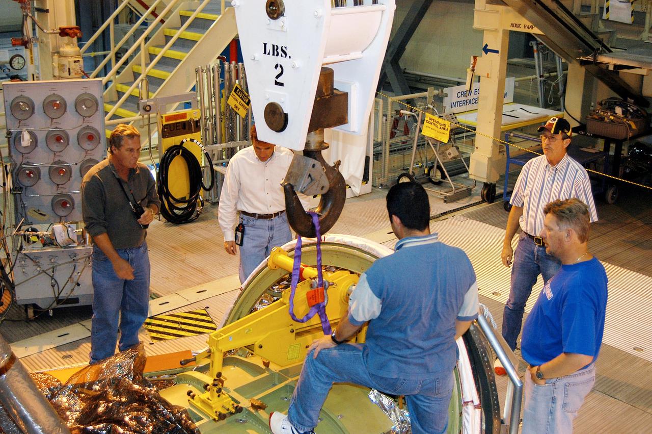 KENNEDY SPACE CENTER, FLA. - Workers in the Orbiter Processing Facility get ready to remove Ground Support Equipment used to install Discovery’s nose cap on Friday.  The nose cap had been removed from the vehicle in the summer of 2003 and returned to the vendor, where it underwent numerous forms of Non-Destructive Evaluation. These tests included X-ray, ultrasound and eddy current to ensure its structural integrity prior to installation on the vehicle. The nose cap was also recoated. Once returned to KSC, new Thermal Protection System blankets were assembled inside of the nose cap and thermography was performed prior to installation on the orbiter.