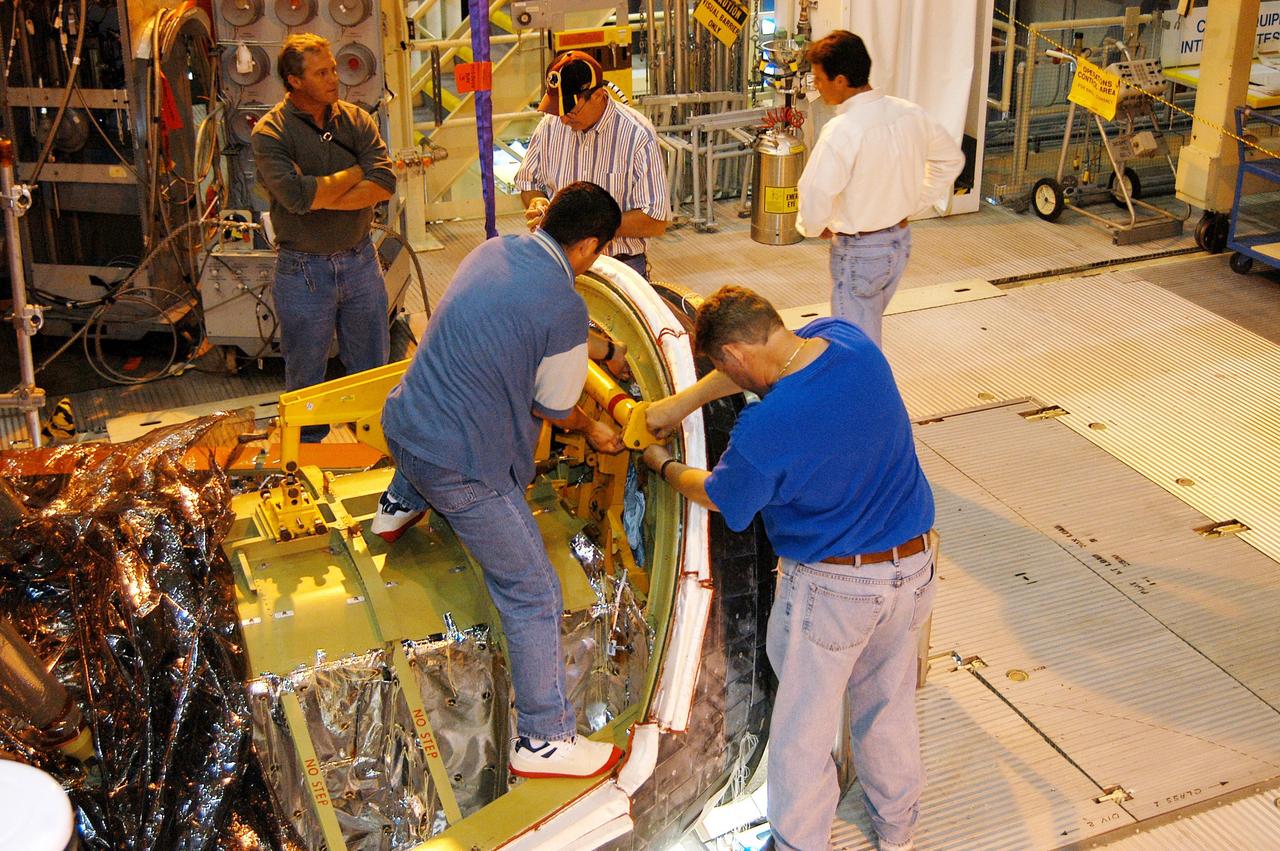 KENNEDY SPACE CENTER, FLA. - Workers in the Orbiter Processing Facility remove Ground Support Equipment used to install Discovery’s nose cap on Friday.  The nose cap had been removed from the vehicle in the summer of 2003 and returned to the vendor, where it underwent numerous forms of Non-Destructive Evaluation. These tests included X-ray, ultrasound and eddy current to ensure its structural integrity prior to installation on the vehicle. The nose cap was also recoated. Once returned to KSC, new Thermal Protection System blankets were assembled inside of the nose cap and thermography was performed prior to installation on the orbiter.