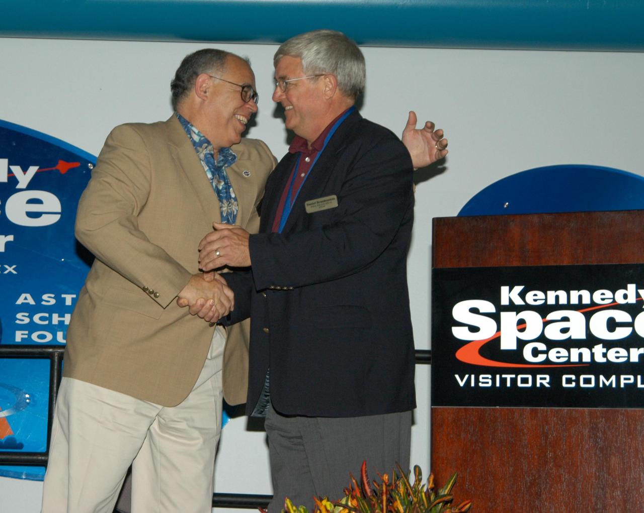 KENNEDY SPACE CENTER, FLA. -- At the Kennedy Space Center Visitor Complex, NASA Deputy Administrator Frederick D. Gregory (left) is congratulated by former NASA astronaut Daniel C. Brandenstein at his induction into the U.S. Astronaut Hall of Fame. Gregory was the first African-American to command a space mission. Also chosen for this honor in 2004 are Kathryn D. Sullivan, the first American woman to walk in space; Richard O. Covey, commander of the Hubble Space Telescope repair mission; Norman E. Thagard, the first American to occupy Russia's Mir space station; and the late Francis R. "Dick" Scobee, commander of the ill-fated 1986 Challenger mission. The U.S. Astronaut Hall of Fame opened in 1990 to provide a place where space travelers could be remembered for their participation and accomplishments in the U.S. space program. To be eligible for induction, an individual must have been a U.S. citizen, a NASA astronaut, and out of the active astronaut corps at least five years. The five inductees join 52 previously honored astronauts from the ranks of the Gemini, Apollo, Skylab, Apollo-Soyuz, and Space Shuttle programs.