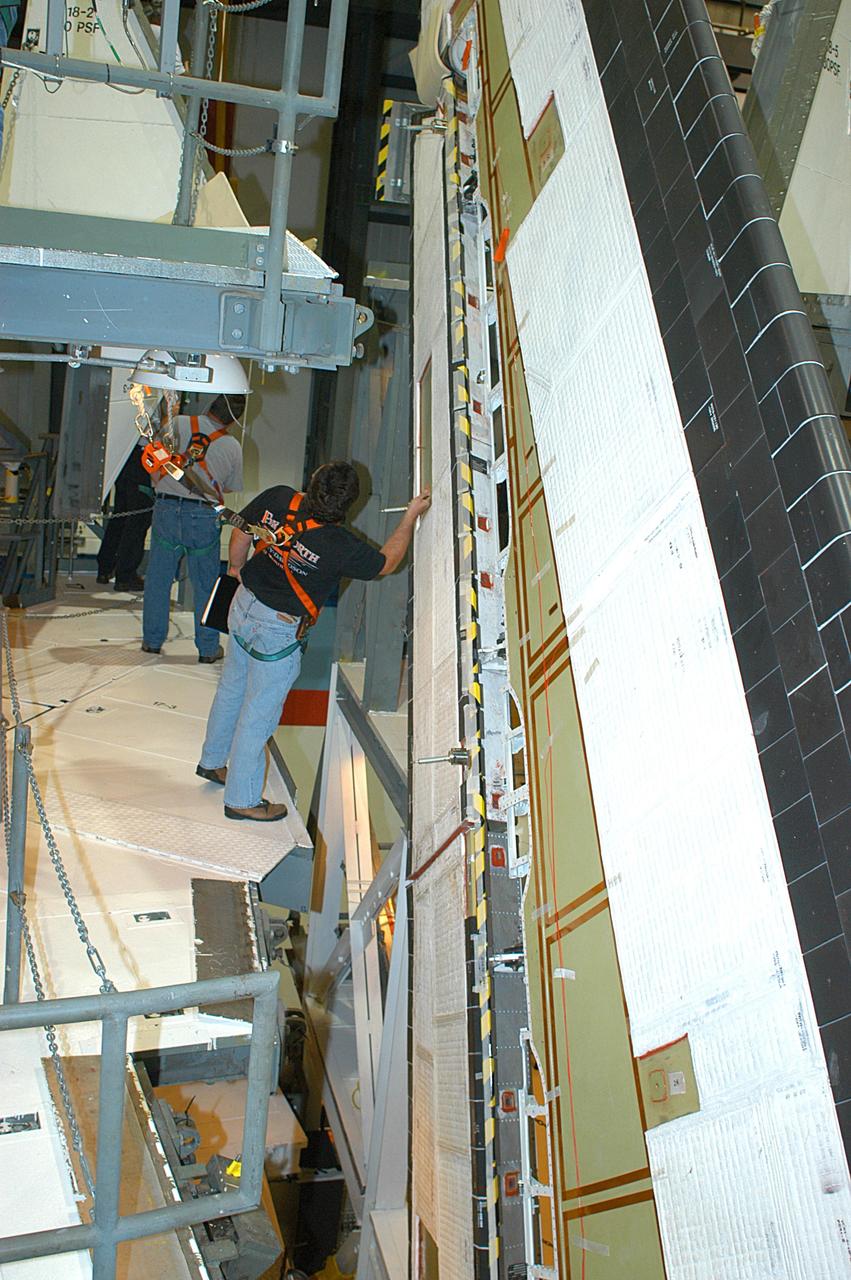 KENNEDY SPACE CENTER, FLA. -- In the Orbiter Processing Facility, a technician looks at the Rudder Speed Brake panel on the vertical tail of orbiter Atlantis. The Rudder Speed Brake is being removed for inspection and maintenance prior to Return to Flight. The vertical tail consists of a structural fin surface made of aluminum, the Rudder Speed Brake surface, a tip and a lower trailing edge.  The rudder splits into two halves to serve as a speed brake. The vertical tail and Rudder Speed Brake are covered with a reusable thermal protection system.  The Rudder Speed Brake is used to guide and slow the Shuttle as it comes in for a landing.