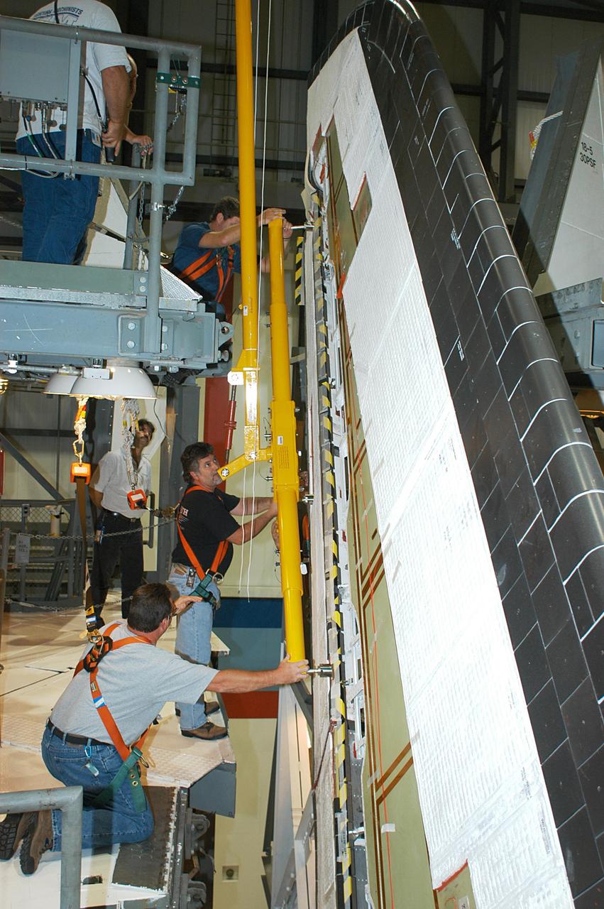 KENNEDY SPACE CENTER, FLA. -- In the Orbiter Processing Facility, workers connect a device onto the vertical tail of the orbiter Atlantis to remove the Rudder Speed Brake panel. The Rudder Speed Brake is being removed for inspection and maintenance prior to Return to Flight. The vertical tail consists of a structural fin surface made of aluminum, the Rudder Speed Brake surface, a tip and a lower trailing edge. The rudder splits into two halves to serve as a speed brake. The vertical tail and Rudder Speed Brake are covered with a reusable thermal protection system. The Rudder Speed Brake is used to guide and slow the Shuttle as it comes in for a landing.