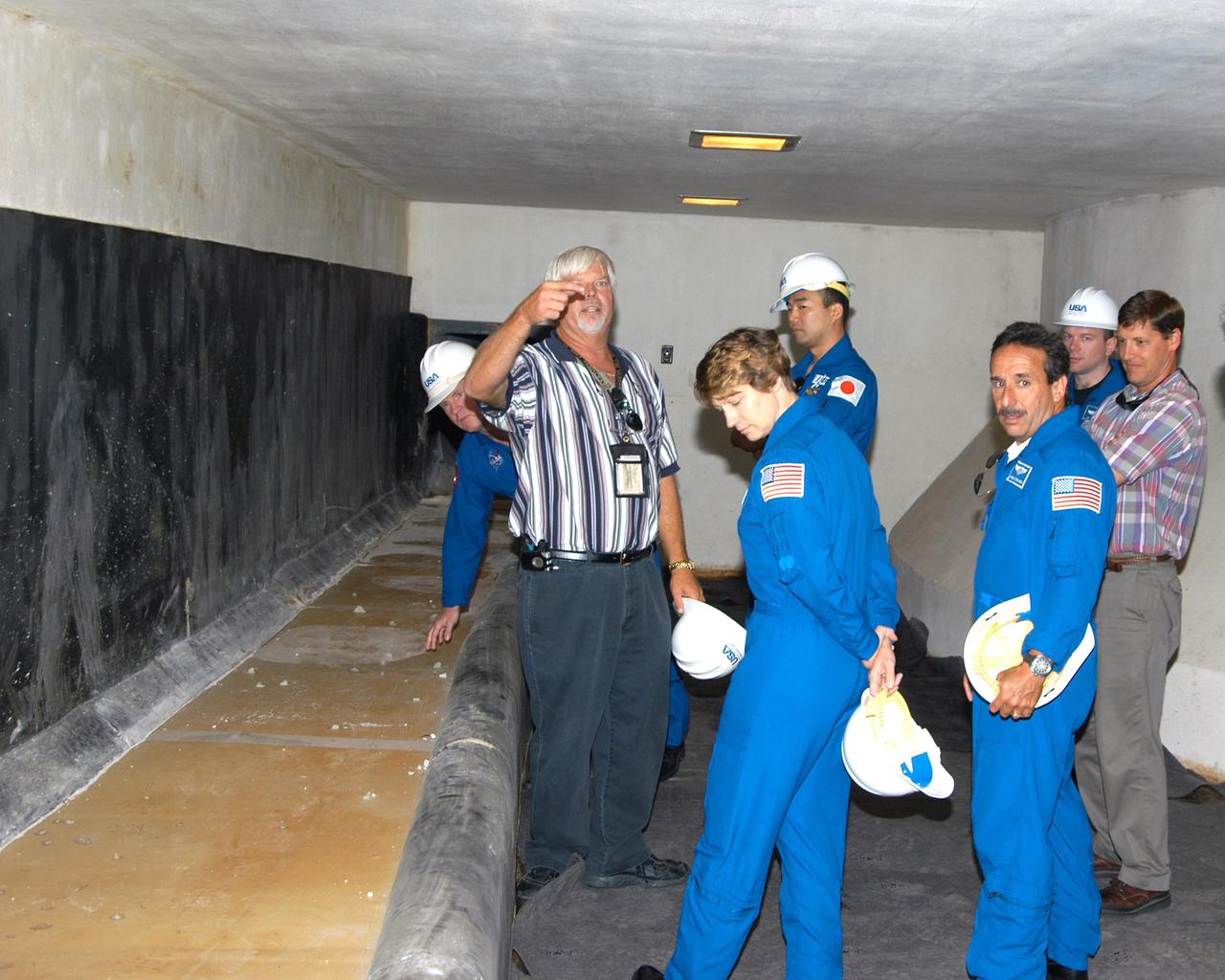 KENNEDY SPACE CENTER, FLA. -- STS-114 crew members tour the Rubber Room at Launch Pad 39A. From left to right are Mission Specialist Andrew Thomas; Steve Leonhard, chief, Pad A Operations, with United Space Alliance (USA); Mission Commander Eileen Collins; Mission Specialists Soichi Noguchi, who represents the Japanese Aerospace and Exploration Agency, and Charles Camarda; Pilot James Kelly; and David Sutherland, manager, Pad A Operations, USA. Located under the launch pad, the steel dome Rubber Room floats on rubber isolators. It was the escape area used during the Apollo launches and it could not be removed when the pad was modified for the Shuttle. In case of an emergency on the pad, the astronauts would slide down a long vertical tube (left) to the Rubber Room and wait for the danger to clear. The STS-114 mission is Logistics Flight 1, which is scheduled to deliver supplies and equipment plus the external stowage platform to the International Space Station.