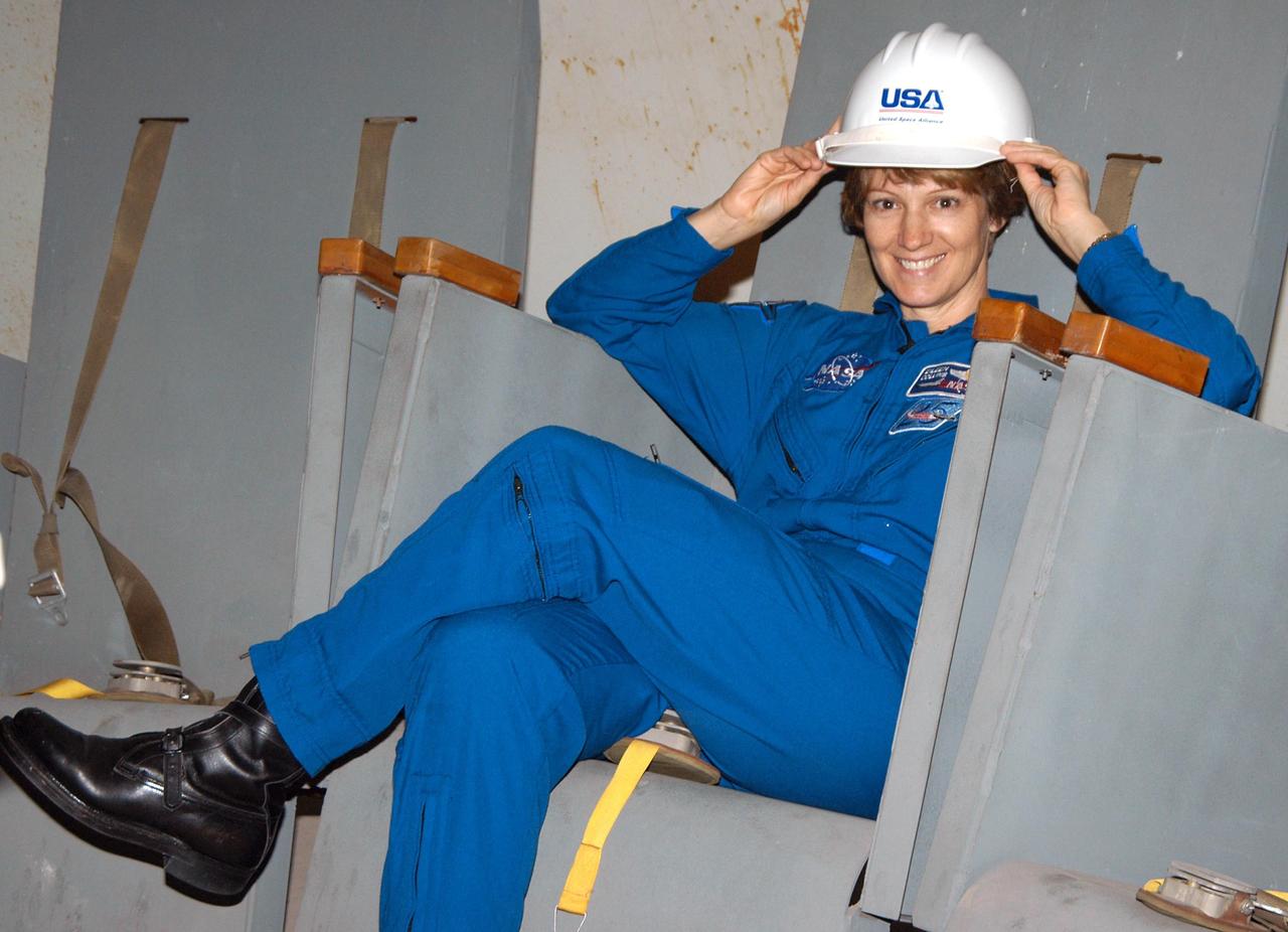 KENNEDY SPACE CENTER, FLA. -- STS-114 Mission Commander Eileen Collins tries out one of the seats in the Rubber Room.  Located under the launch pad, the steel dome Rubber Room floats on rubber isolators. It was the escape area used during the Apollo launches and it could not be removed when the pad was modified for the Shuttle. In case of an emergency on the pad, the astronauts would slide down the long vertical tube to the Rubber Room, strap themselves into the seats and wait for the danger to clear. The STS-114 mission is Logistics Flight 1, which is scheduled to deliver supplies and equipment plus the external stowage platform to the International Space Station.