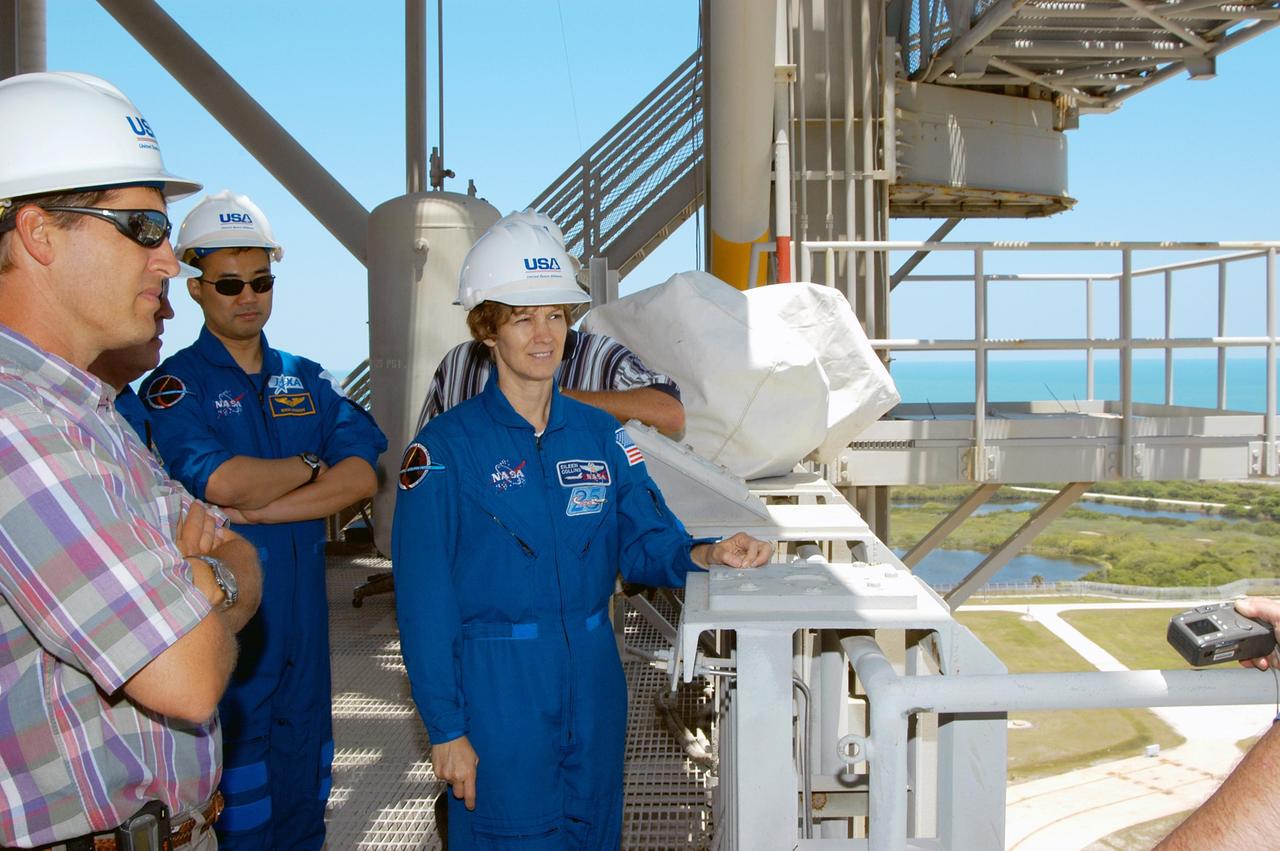 KENNEDY SPACE CENTER, FLA. -- David Sutherland (left), manager, Pad A Operations (with United Space Alliance), accompanies STS-114 crew members on a tour of the pad.  In the center is Mission Specialist Soichi Noguchi, who represents the Japanese Aerospace and Exploration Agency; at right is Mission Commander Eileen Collins.  Beyond the pad is the aqua blue Atlantic Ocean, glimpsed between the railing on an upper level of the Fixed Service Structure on Launch Pad 39A. The STS-114 mission is Logistics Flight 1, which is scheduled to deliver supplies and equipment plus the external stowage platform to the International Space Station.