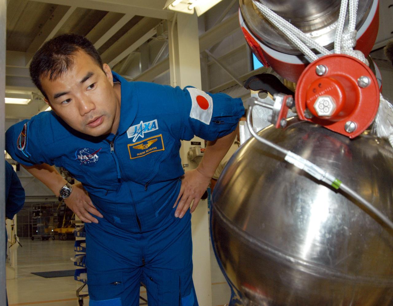 KENNEDY SPACE CENTER, FLA. -- STS-114 Mission Specialist Soichi Noguchi looks closely at low pressure oxidizer duct in the Space Shuttle Main Engine Shop at KSC.  He and other crew members are touring several areas on the Center.  The STS-114 mission is Logistics Flight 1, which is scheduled to deliver supplies and equipment plus the external stowage platform to the International Space Station.