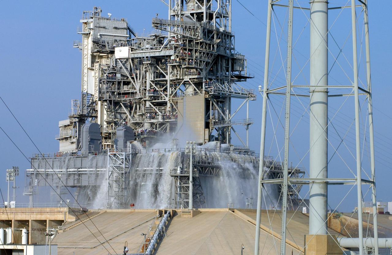 KENNEDY SPACE CENTER, FLA. -- For the fourth time in Space Shuttle Program history, 350,000 gallons of water are released on a Mobile Launcher Platform (MLP) at Launch Pad 39A during a water sound suppression test. This test is being conducted following the replacement of the six main system valves, which had been in place since the beginning of the Shuttle Program and had reached the end of their service life. Also, the hydraulic portion of the valve actuators has been redesigned and simplified to reduce maintenance costs. The sound suppression water system is installed on the launch pads to protect the orbiter and its payloads from damage by acoustical energy reflected from the MLP during launch. The system includes an elevated water tank with a capacity of 300,000 gallons. The tank is 290 feet high and stands on the northeast side of the Pad. The water is released just before the ignition of the orbiter's three main engines and twin solid rocket boosters, and flows through parallel 7-foot-diameter pipes to the Pad area.