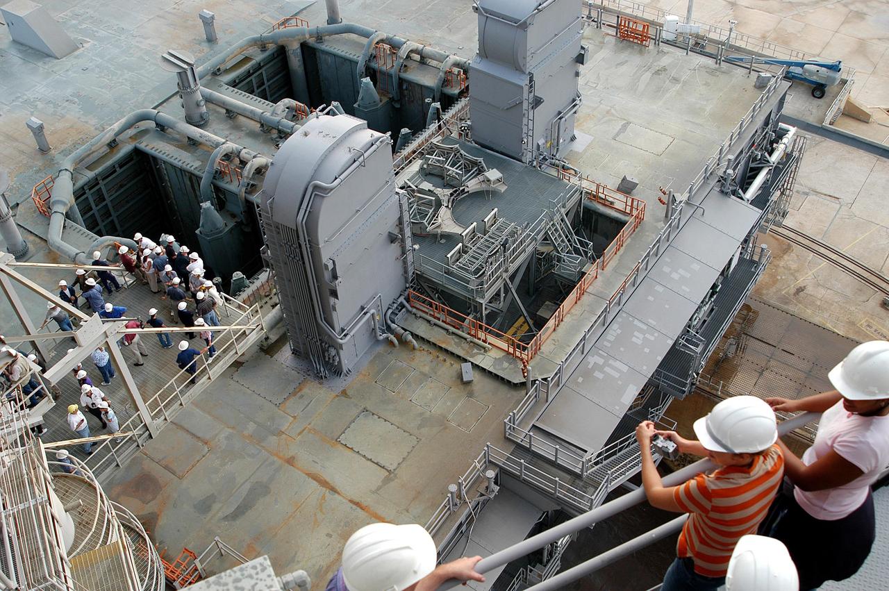 KENNEDY SPACE CENTER, FLA. -- From vantage points on the Fixed Service Structure (left) on Launch Pad 39A, workers and the media look down upon the Mobile Launcher Platform (MLP) waiting for the start of a water sound suppression test. This test is being conducted following the replacement of the six main system valves, which had been in place since the beginning of the Shuttle Program and had reached the end of their service life. Also, the hydraulic portion of the valve actuators has been redesigned and simplified to reduce maintenance costs. The sound suppression water system is installed on the launch pads to protect the orbiter and its payloads from damage by acoustical energy reflected from the MLP during launch. The system includes an elevated water tank with a capacity of 300,000 gallons. The tank is 290 feet high and stands on the northeast side of the Pad. The water is released just before the ignition of the orbiter's three main engines and twin solid rocket boosters, and flows through parallel 7-foot-diameter pipes to the Pad area.
