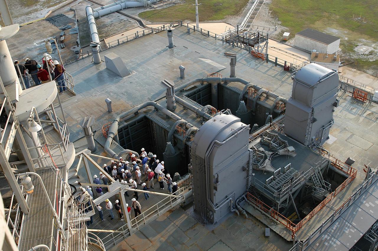 KENNEDY SPACE CENTER, FLA. -- From vantage points on the Fixed Service Structure (left) on Launch Pad 39A, workers and the media look down upon the Mobile Launcher Platform (MLP) waiting for the start of a water sound suppression test. This test is being conducted following the replacement of the six main system valves, which had been in place since the beginning of the Shuttle Program and had reached the end of their service life. Also, the hydraulic portion of the valve actuators has been redesigned and simplified to reduce maintenance costs. The sound suppression water system is installed on the launch pads to protect the orbiter and its payloads from damage by acoustical energy reflected from the MLP during launch. The system includes an elevated water tank with a capacity of 300,000 gallons. The tank is 290 feet high and stands on the northeast side of the Pad. The water is released just before the ignition of the orbiter's three main engines and twin solid rocket boosters, and flows through parallel 7-foot-diameter pipes to the Pad area.