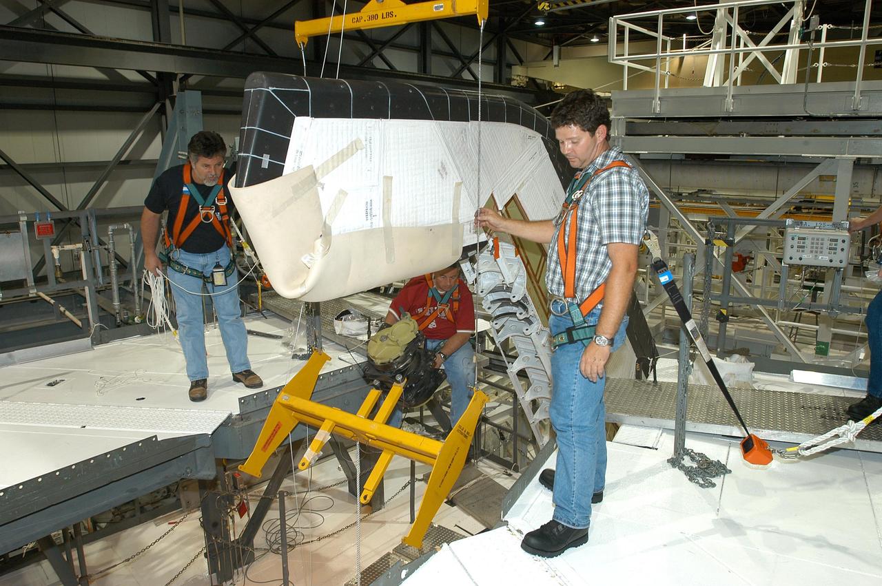 KENNEDY SPACE CENTER, FLA. -- Workers ensure the safe removal of a Rudder Speed Brake Actuator from the orbiter Atlantis. This and three other actuators are being shipped to the vendor for inspection. An actuator is a motor that moves the tail rudder back and forth to help steer it during landing and brake its speed. The vertical tail consists of a structural fin surface made of aluminum, the Rudder Speed Brake surface, a tip and a lower trailing edge. The rudder splits into two halves to serve as a speed brake. The vertical tail and Rudder Speed Brake are covered with a reusable thermal protection system. Atlantis is undergoing maintenance and inspection in the Orbiter Processing Facility for a future mission.