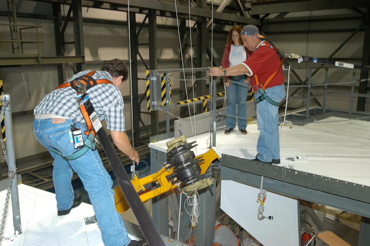 KENNEDY SPACE CENTER, FLA. -- Workers ensure the safe removal of a Rudder Speed Brake Actuator from the orbiter Atlantis. This and three other actuators are being shipped to the vendor for inspection. An actuator is a motor that moves the tail rudder back and forth to help steer it during landing and brake its speed. The vertical tail consists of a structural fin surface made of aluminum, the Rudder Speed Brake surface, a tip and a lower trailing edge. The rudder splits into two halves to serve as a speed brake. The vertical tail and Rudder Speed Brake are covered with a reusable thermal protection system. Atlantis is undergoing maintenance and inspection in the Orbiter Processing Facility for a future mission.