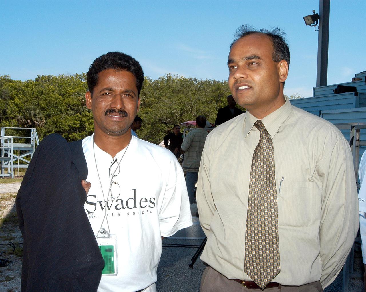 KENNEDY SPACE CENTER, FLA. -- Sashikant Dhawan (left), costume director with a film crew from India, and Shirish R. Patel (right), with KSC’s International Space Station Payload Processing, pose for a photo near the viewing stands at the NASA News Center.  The crew spent several days at KSC filming at various sites for the movie “Swades,” a story about India’s brain-drain.  The writer and director is Ashutosh Gowariker.  The lead actors are Shahrukh Khan and Gayatri Joshi. Sunita Gowariker is executive producer.