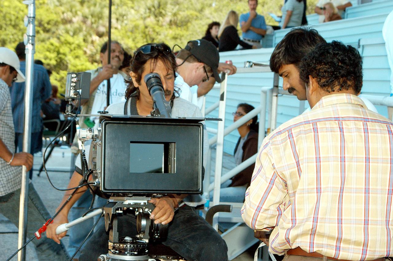 KENNEDY SPACE CENTER, FLA. -- Mahesh Aney, who is director of photography on a film crew from India, sets up a camera at the stands near the NASA News Center.  The crew spent several days at KSC filming at various sites for the movie “Swades,” a story about India’s brain-drain.  The writer and director is Ashutosh Gowariker.  The lead actors are Shahrukh Khan and Gayatri Joshi. Sunita Gowariker is executive producer.