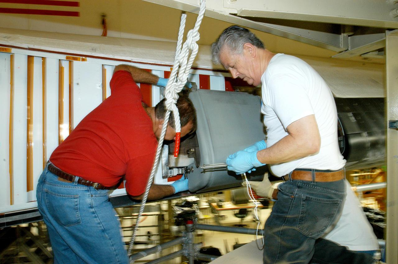 KENNEDY SPACE CENTER, FLA. -- In the Orbiter Processing Facility, technicians Mike McCall (left) and Jake Jacobson install a reinforced carbon carbon panel on the right wing of Space Shuttle Discovery. The next flight planned for Discovery is the STS-114 mission on Logistics Flight 1 to deliver supplies and equipment, as well as the external stowage platform, to the International Space Station. STS-114 will be the mission that returns the Space Shuttle to flight status and is scheduled for no earlier than March 2005.