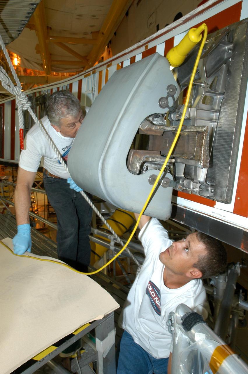 KENNEDY SPACE CENTER, FLA. -- In the Orbiter Processing Facility, technicians Jake Jacobson (left) and Billy Barecka install a reinforced carbon carbon panel on the right wing of Space Shuttle Discovery. The next flight planned for Discovery is the STS-114 mission on Logistics Flight 1 to deliver supplies and equipment, as well as the external stowage platform, to the International Space Station. STS-114 will be the mission that returns the Space Shuttle to flight status and is scheduled for no earlier than March 2005.