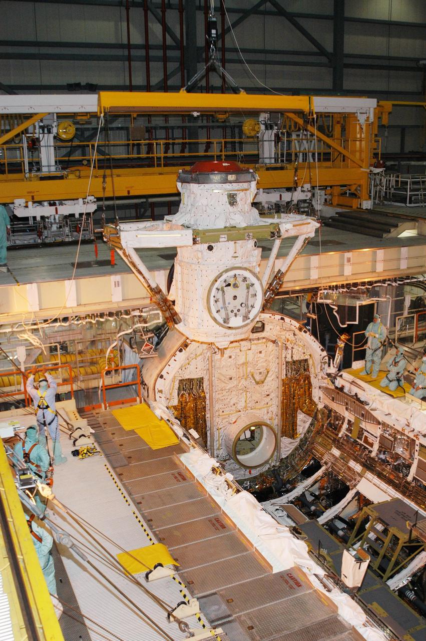 KENNEDY SPACE CENTER, FLA. -- Discovery’s airlock is lowered toward the orbiter’s payload bay for installation.  The airlock is sized to accommodate two fully suited flight crew members simultaneously.  Support functions include airlock depressurization and repressurization, extravehicular activity equipment recharge, liquid-cooled garment water cooling, EVA equipment checkout, and communications.  Discovery is designated as the Return to Flight vehicle for mission STS-114, no earlier than March 2005.  STS-114 mission is Logistics Flight 1, which is scheduled to deliver supplies and equipment plus the external stowage platform to the International Space Station.