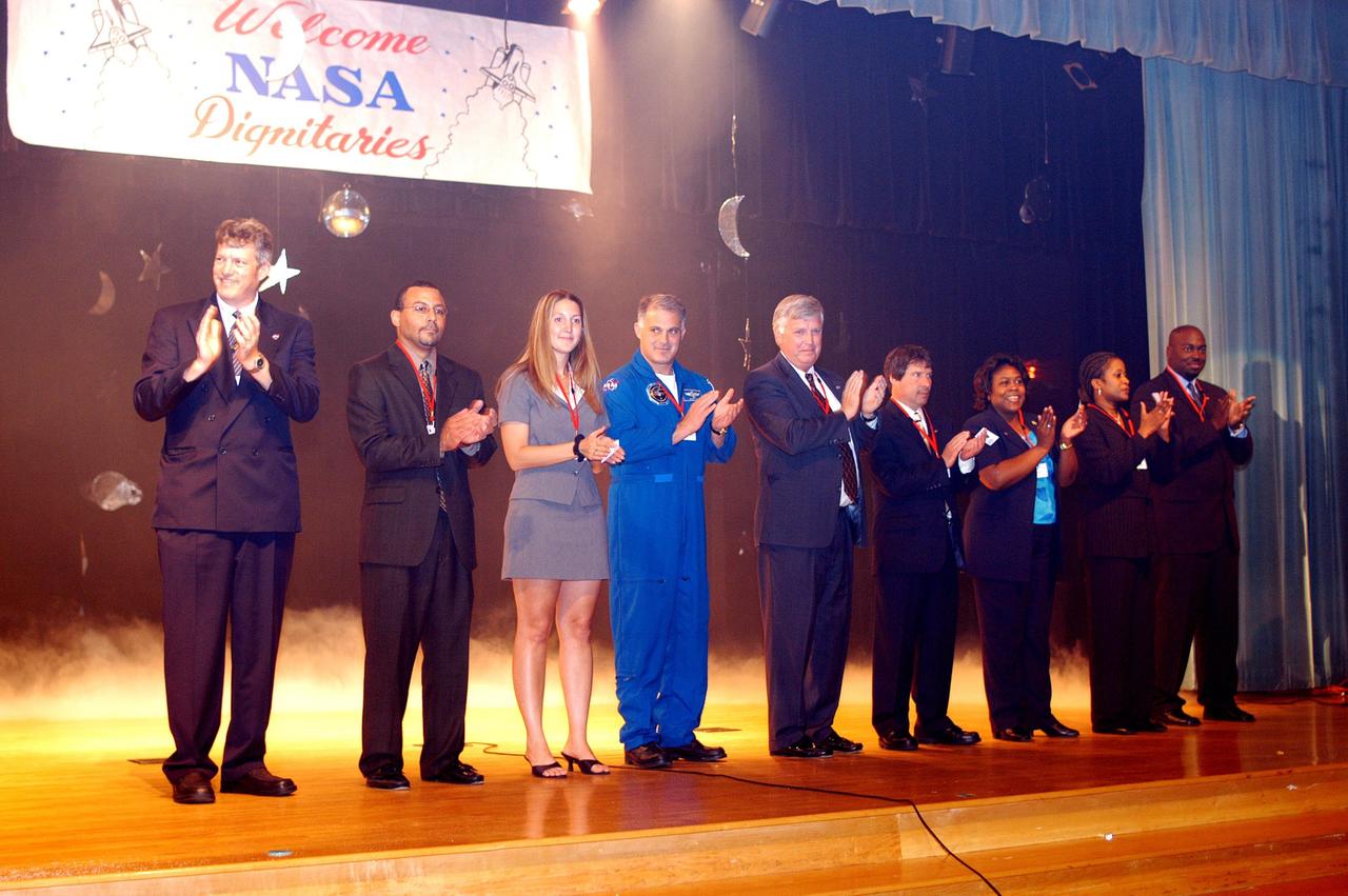KENNEDY SPACE CENTER, FLA. -- During a visit to Howard A. Doolin Middle School, Miami, Fla., Center Director Jim Kennedy and other NASA and KSC representatives applaud faculty and students from the stage. From left to right are Jim Gerard, Aerospace Education Services Program (AESP) representative; Steve Lewis, assistant to Kennedy; Amber Marek, with KSC External Relations; David Wolf, astronaut; Kennedy; Les Gold, AESP representative; Burdette Brown; and Patricia Leonard and Clarence Bostic, Education Programs and University Research Division. Doolin Middle School is one of 100 to take part in the NASA Explorer Schools program. Kennedy is talking with students, the next generation of explorers, about our destiny as explorers, NASA’s stepping stone approach to exploring Earth, the Moon, Mars and beyond, how space impacts our lives, and how people and machines rely on each other in space.
