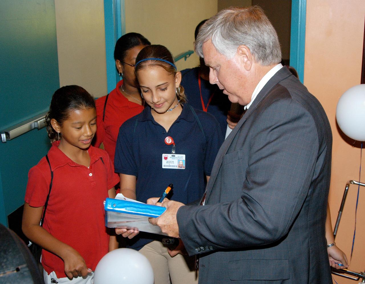 KENNEDY SPACE CENTER, FLA. -- After his presentation, Center Director Jim Kennedy signs a memento for a student at Howard A. Doolin Middle School, Miami, Fla. The school is one of 100 taking part in the NASA Explorer Schools (NES) program. Kennedy visited the school to share America’s new vision for space exploration with the next generation of explorers. He is talking with students in Florida and Georgia Explorer Schools about our destiny as explorers, NASA’s stepping stone approach to exploring Earth, the Moon, Mars and beyond, how space impacts our lives, and how people and machines rely on each other in space.