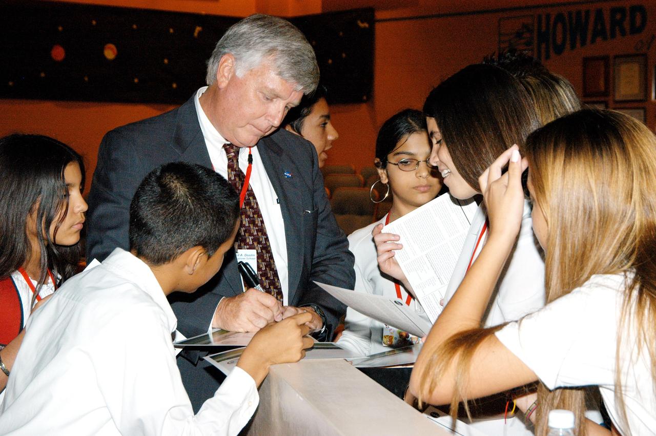KENNEDY SPACE CENTER, FLA. -- After his presentation, students at Howard A. Doolin Middle School, Miami, Fla., gather around Center Director Jim Kennedy as he signs a memento for a student. The school is one of 100 taking part in the NASA Explorer Schools (NES) program. Kennedy visited the school to share America’s new vision for space exploration with the next generation of explorers. He is talking with students in Florida and Georgia Explorer Schools about our destiny as explorers, NASA’s stepping stone approach to exploring Earth, the Moon, Mars and beyond, how space impacts our lives, and how people and machines rely on each other in space.
