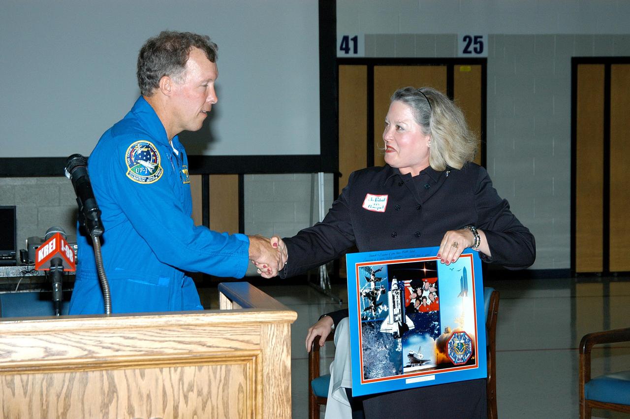 KENNEDY SPACE CENTER, FLA. -- Astronaut Dom Gorie presents a photo montage to Jo Peukert, principal of Trojan Intermediate School in Potosi, Mo. Gorie accompanied KSC Deputy Director Dr. Woodrow Whitlow on a visit to the school to share America’s new vision for space exploration with the next generation of explorers. They are talking with students about our destiny as explorers, NASA’s stepping stone approach to exploring Earth, the Moon, Mars and beyond, how space impacts our lives, and how people and machines rely on each other in space.  Students from three area schools — Potosi High School, John Evans Middle School and Trojan — are on a team taking part in NASA’s Explorer Schools program.