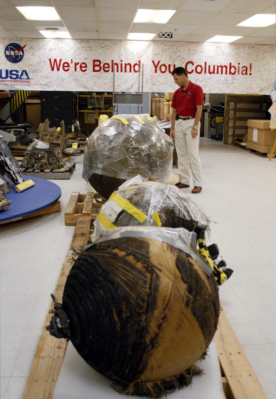 KENNEDY SPACE CENTER, FLA.  -  In the Vehicle Assembly Building (VAB), Scott Thurston looks at pieces of Columbia debris being prepared for transfer to the shipping facility before their delivery to The Aerospace Corporation in El Segundo, Calif.  Thurston is the Columbia debris coordinator.  The pieces have been released for loan to the non-governmental agency for testing and research.   The Aerospace Corporation requested and will receive graphite/epoxy honeycomb skins from an Orbital Maneuvering System pod, Main Propulsion System Helium tanks, a Reaction Control System Helium tank and a Power Reactant Storage Distribution system tank. The company will use the parts to study re-entry effects on composite materials. NASA notified the Columbia crew’s families about the loan before releasing the items for study.  Researchers believe the testing will show how materials are expected to respond to various heating and loads' environments. The findings will help calibrate tools and models used to predict hazards to people and property from reentering hardware. The Aerospace Corporation will have the debris for one year to perform analyses to estimate maximum temperatures during reentry based upon the geometry and mass of the recovered composite.  Columbia’s debris is stored in the VAB.
